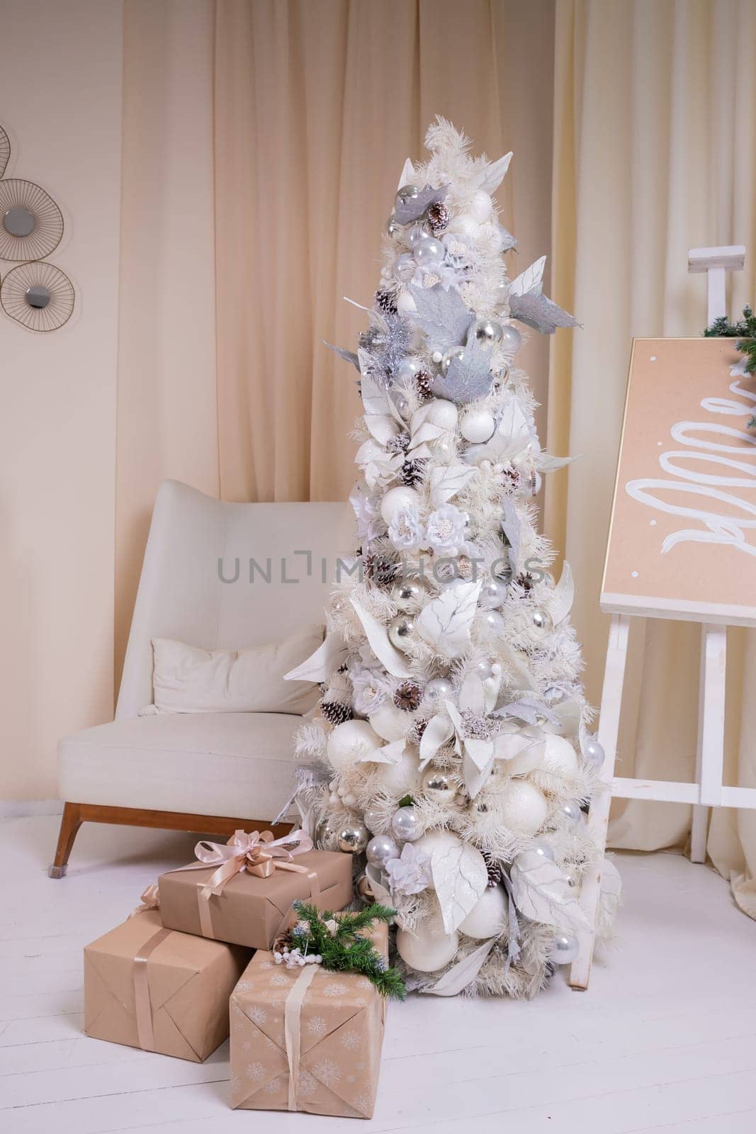 Decorated gold Christmas tree with golden patchwork ornament artificial star hearts presents for new year in white interior