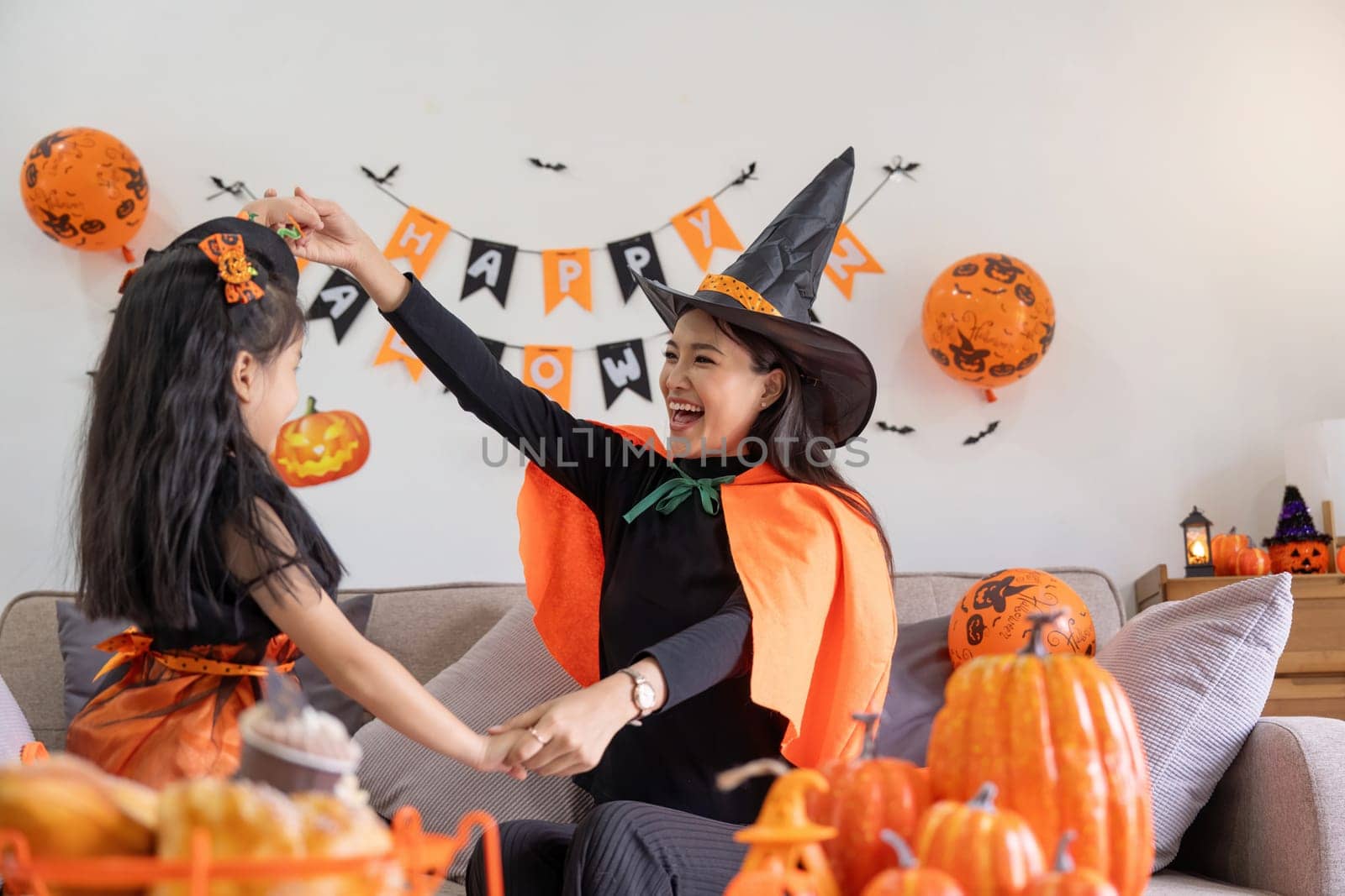 Happy family mother and child happy girl with Halloween at home together beautifully decorated. Mother teasingly playing with daughter.