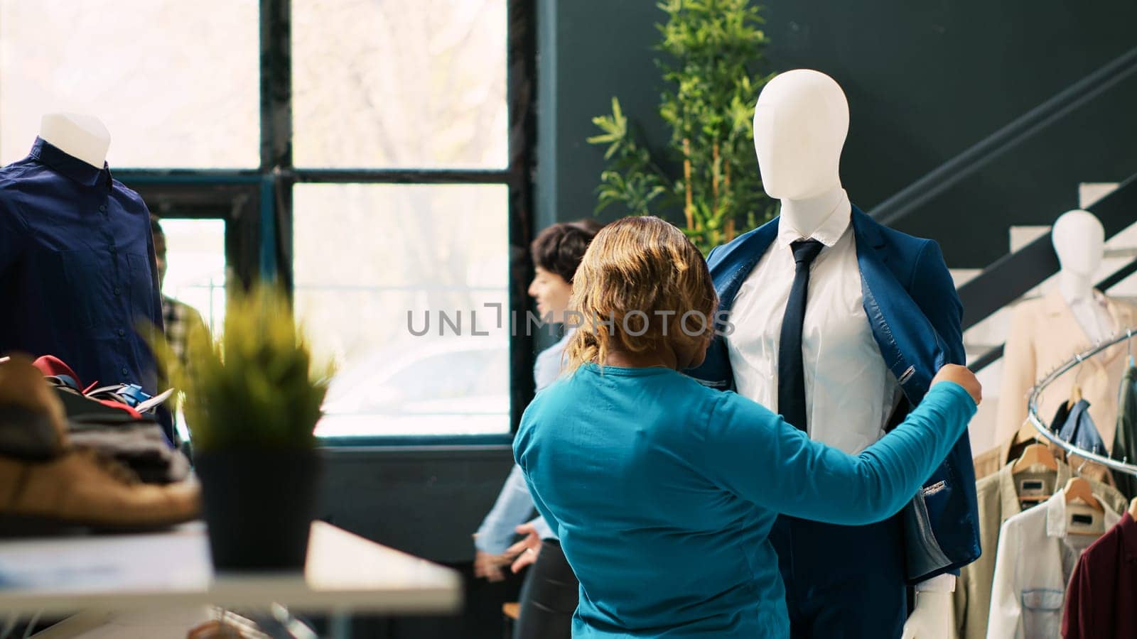 African american client looking at formal suit, checking clothes material in modern boutique. Shopaholic woman shopping for fashionable merchandise, buying stylish shirt. Fashion concept