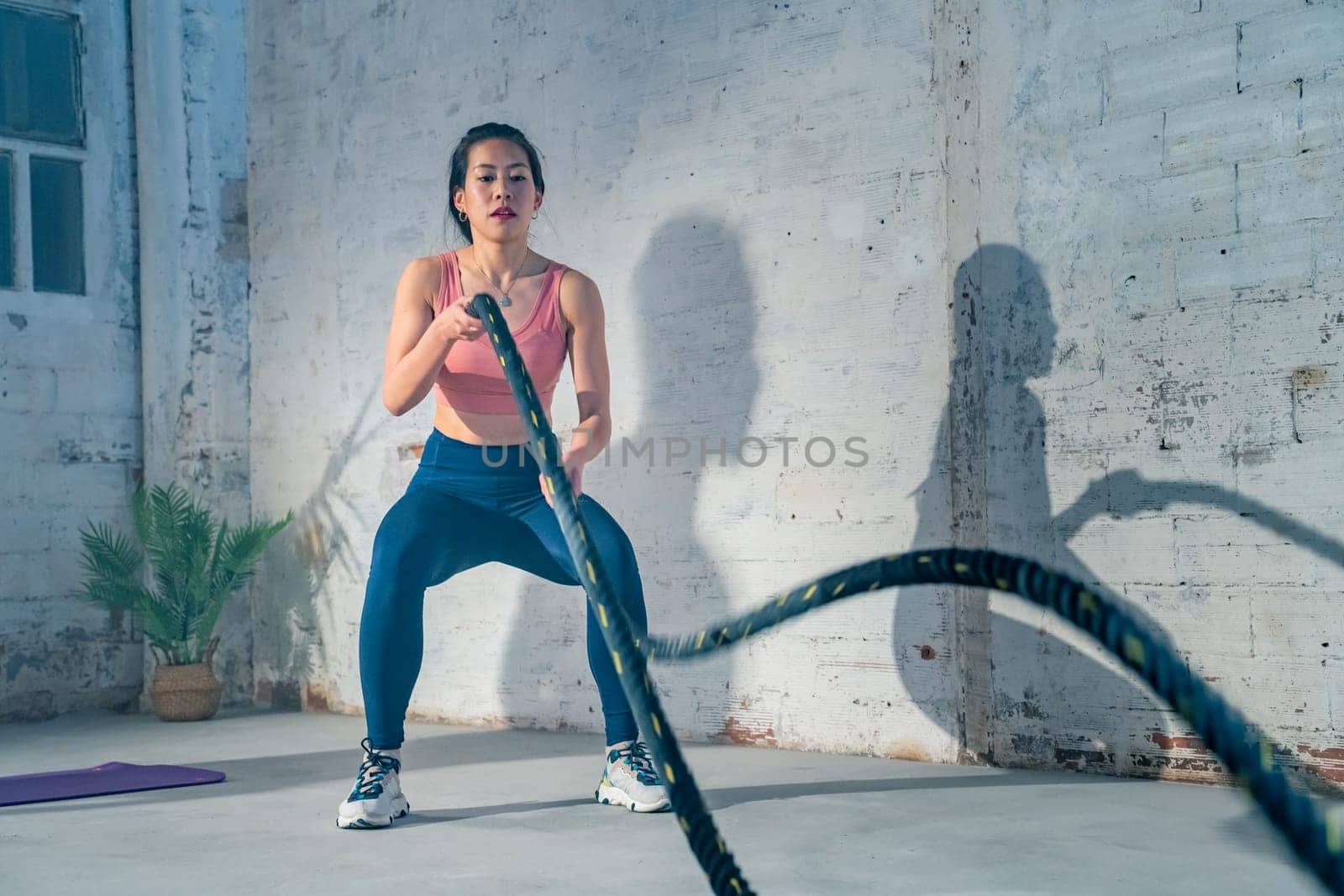 Fitness Chinese athlete training using battle ropes intense workout exercise in gym healthy lifestyle bodybuilding endurance practice in slow motion. High quality 4k footage