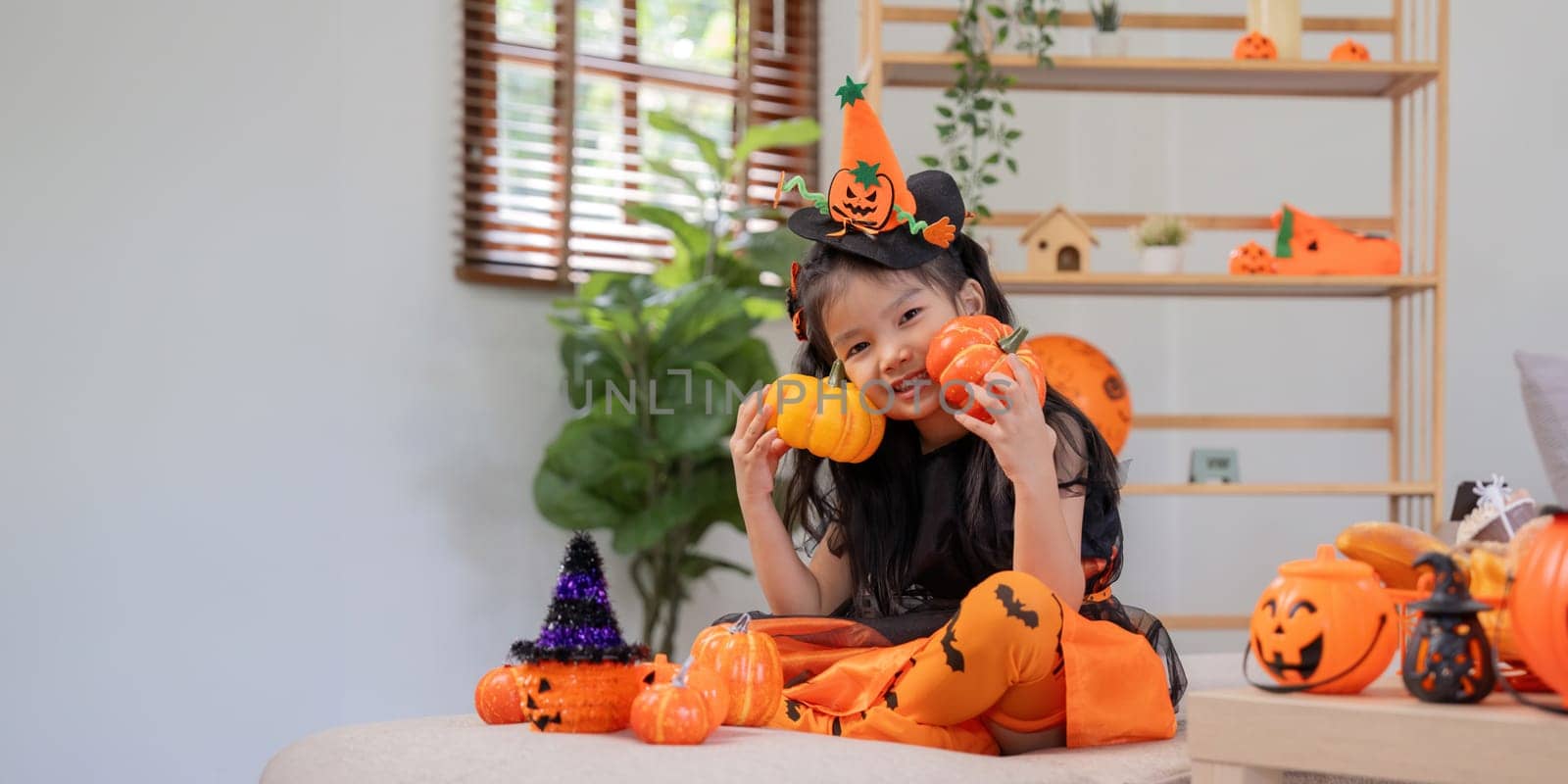 Cute little child girl with pumpkin balloon. Happy family preparing for Halloween.