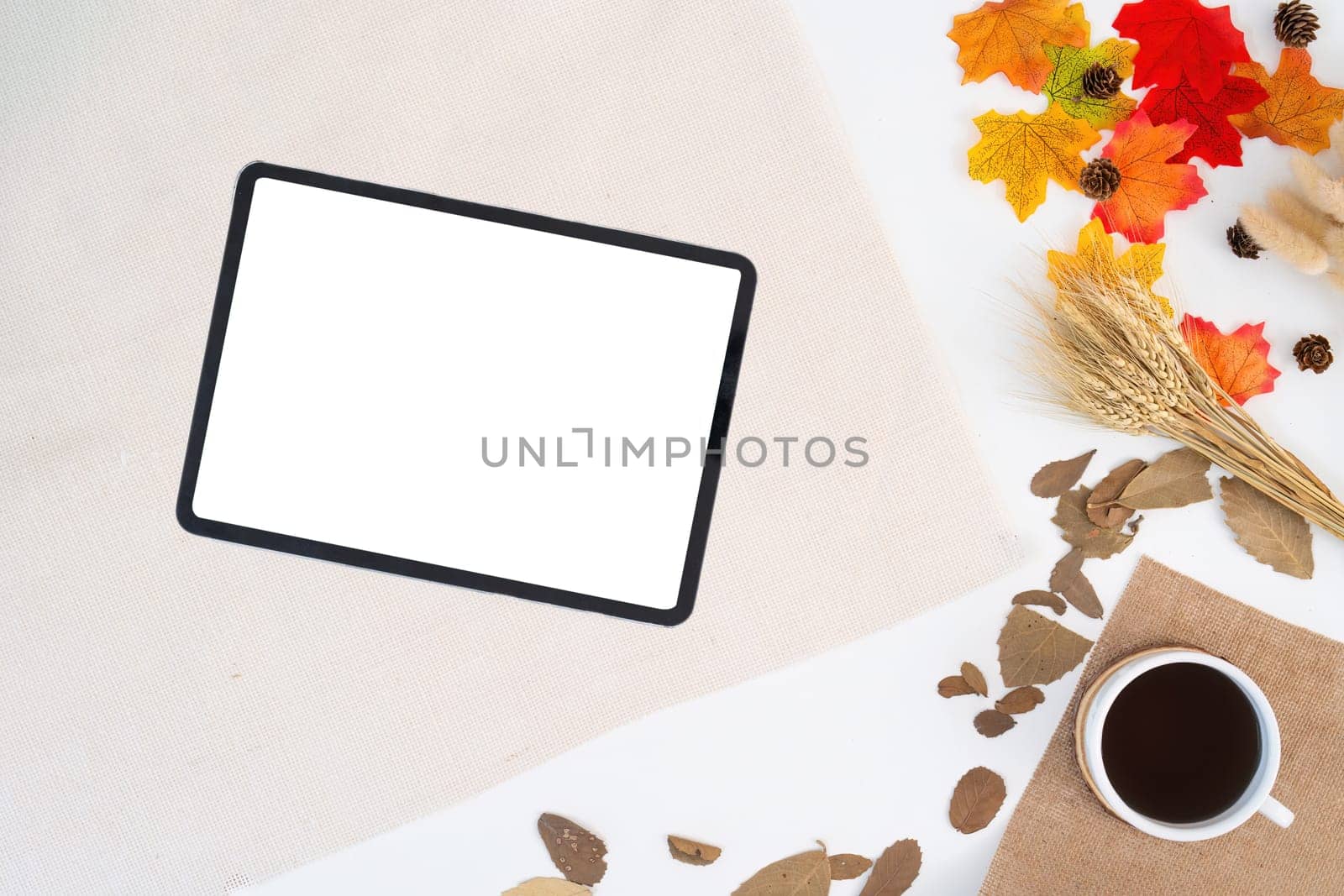 Workspace with blank copy space tablet mockup, notepad, blanket, envelopes, coffee cup, leaves on autumn background. work concept, cosy, cozy, seasonal autumn concept.