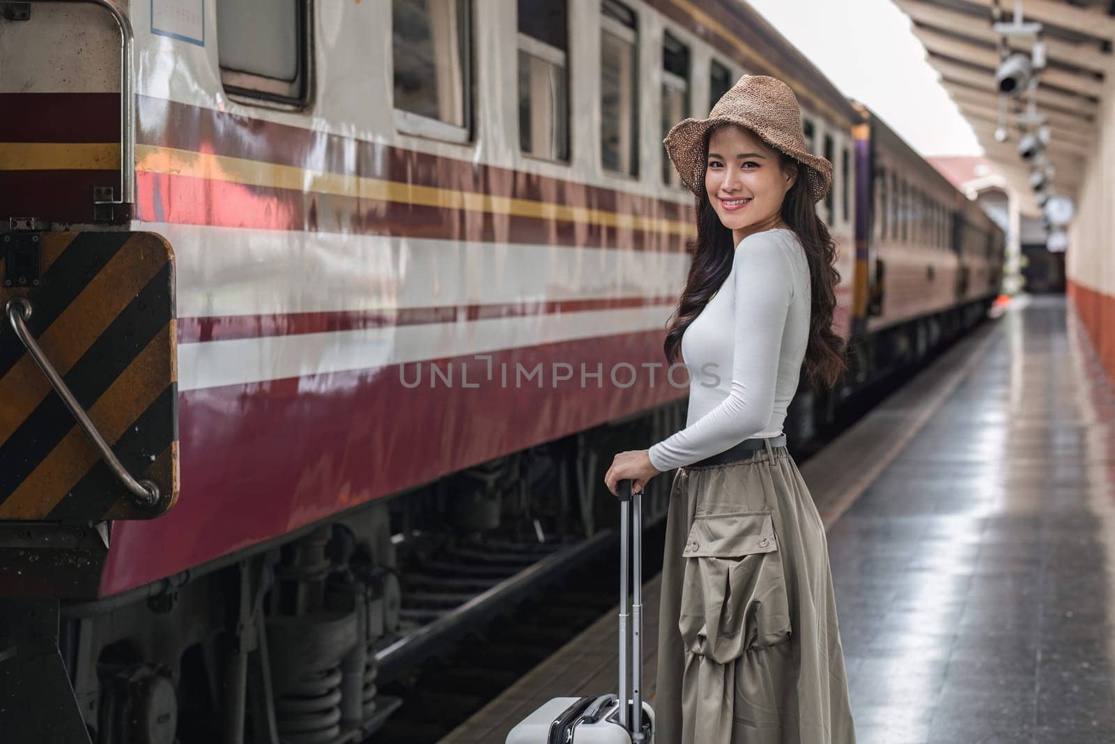 young woman holding a suitcase Happy to travel on holiday by train. by wichayada