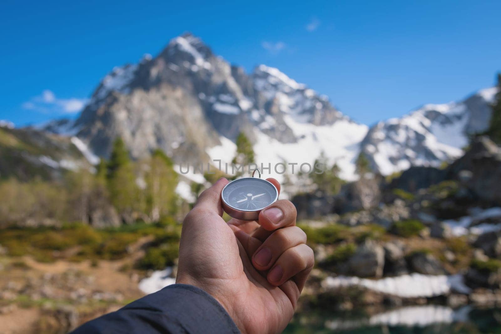 Snow-capped mountains and a tourist hand with an old metal compass in the foreground. Nature reserve, landscape photography.