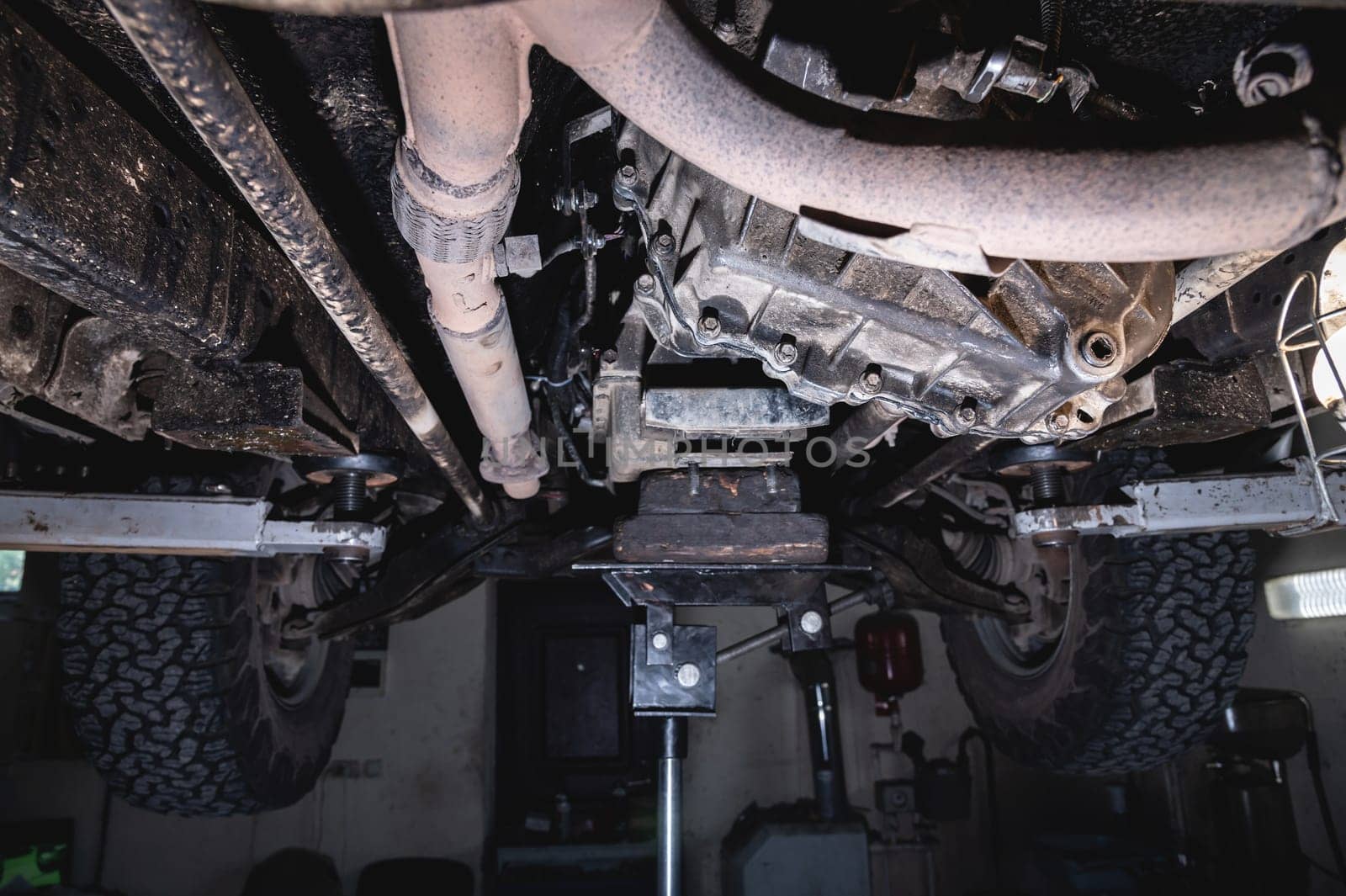 View of the off-road car from below on the lift. Auto service center. Vehicle maintenance.