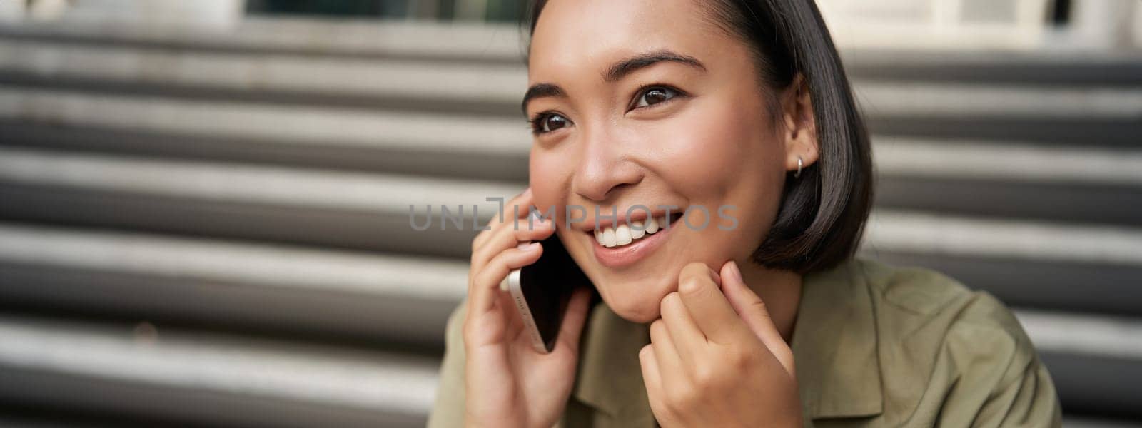 Close up portrait of asian girl talks on mobile phone. Young woman having a phone call, using her telephone by Benzoix