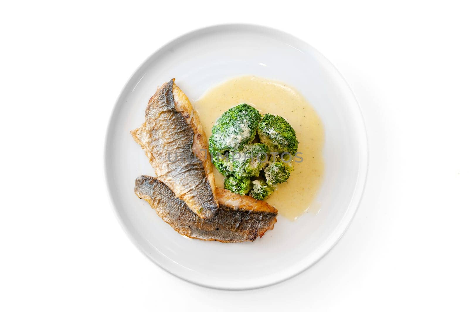 Dorado or sea bass fillet in cream sauce with broccoli on a white plate. High quality photo