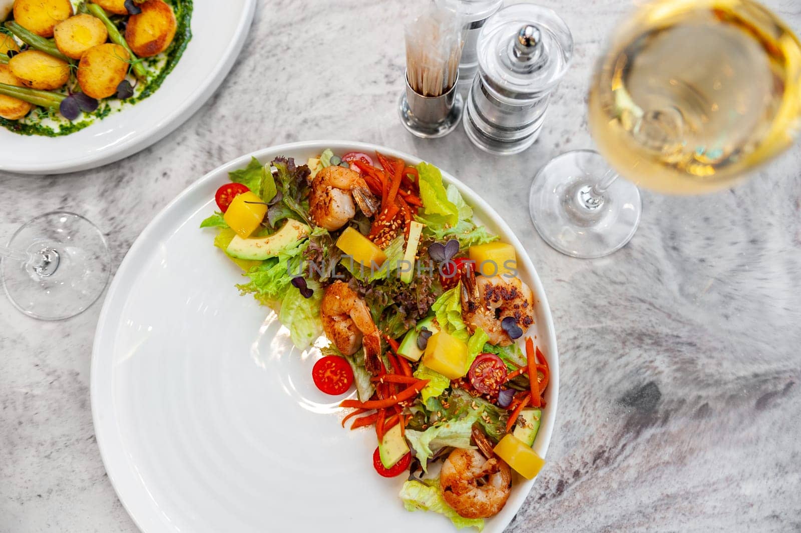 Salad with fried shrimp, mango, avocado and cherry tomatoes on a white plate. High quality photo