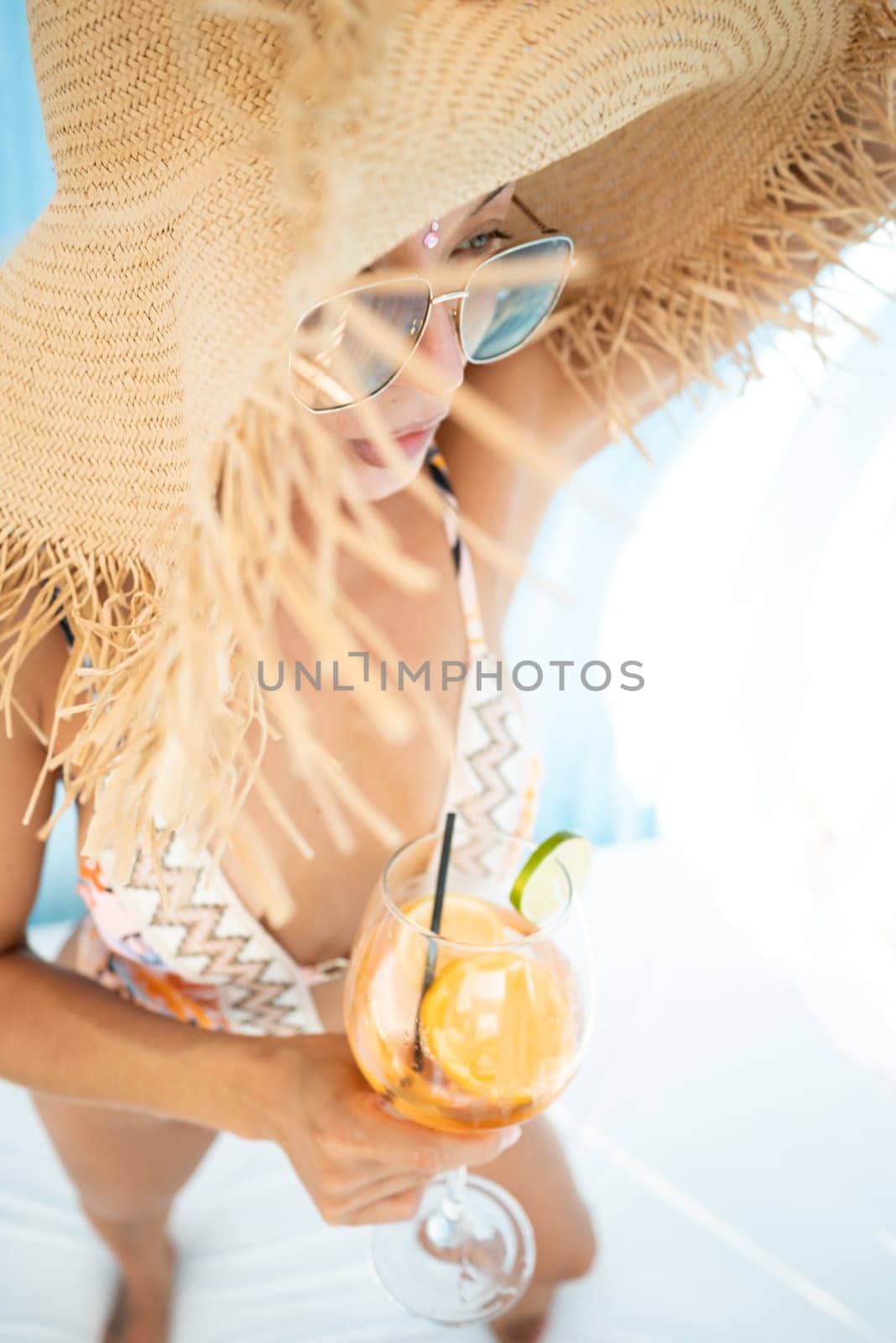 sexy young girl in a straw hat on vacation drinks a cocktail, smiles, gets high and enjoys life in the summer by Rotozey