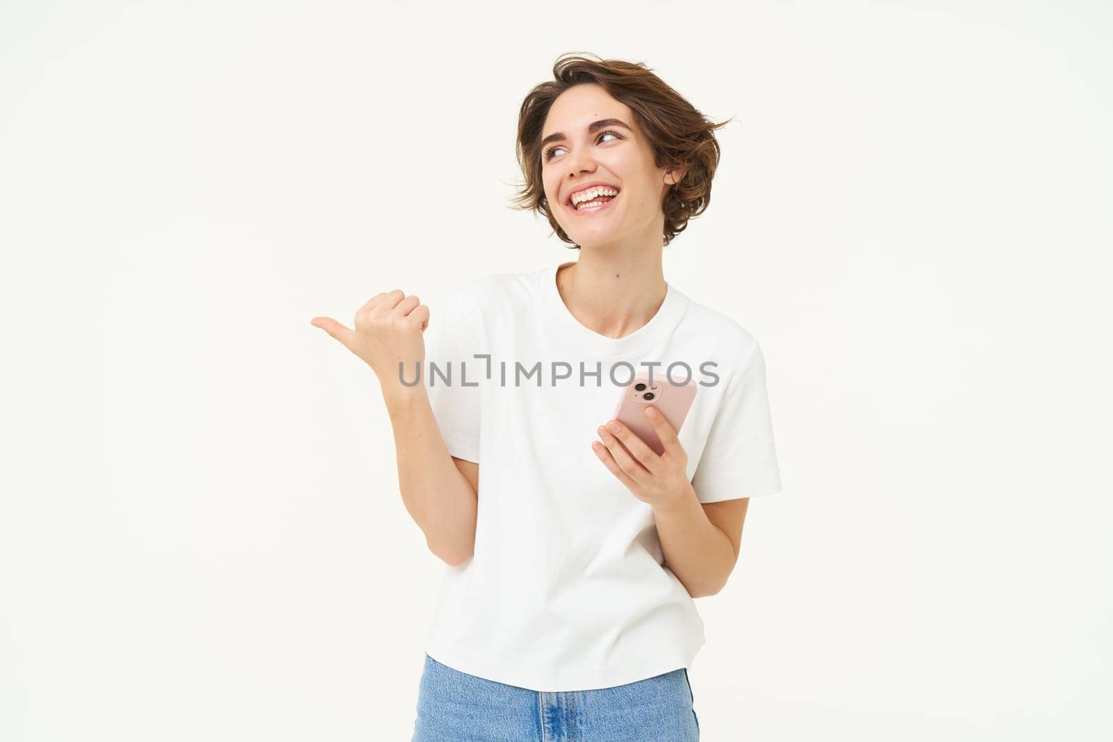 Portrait of woman with smartphone, using mobile phone and pointing at banner, showing text advertisement, standing isolated against white background.