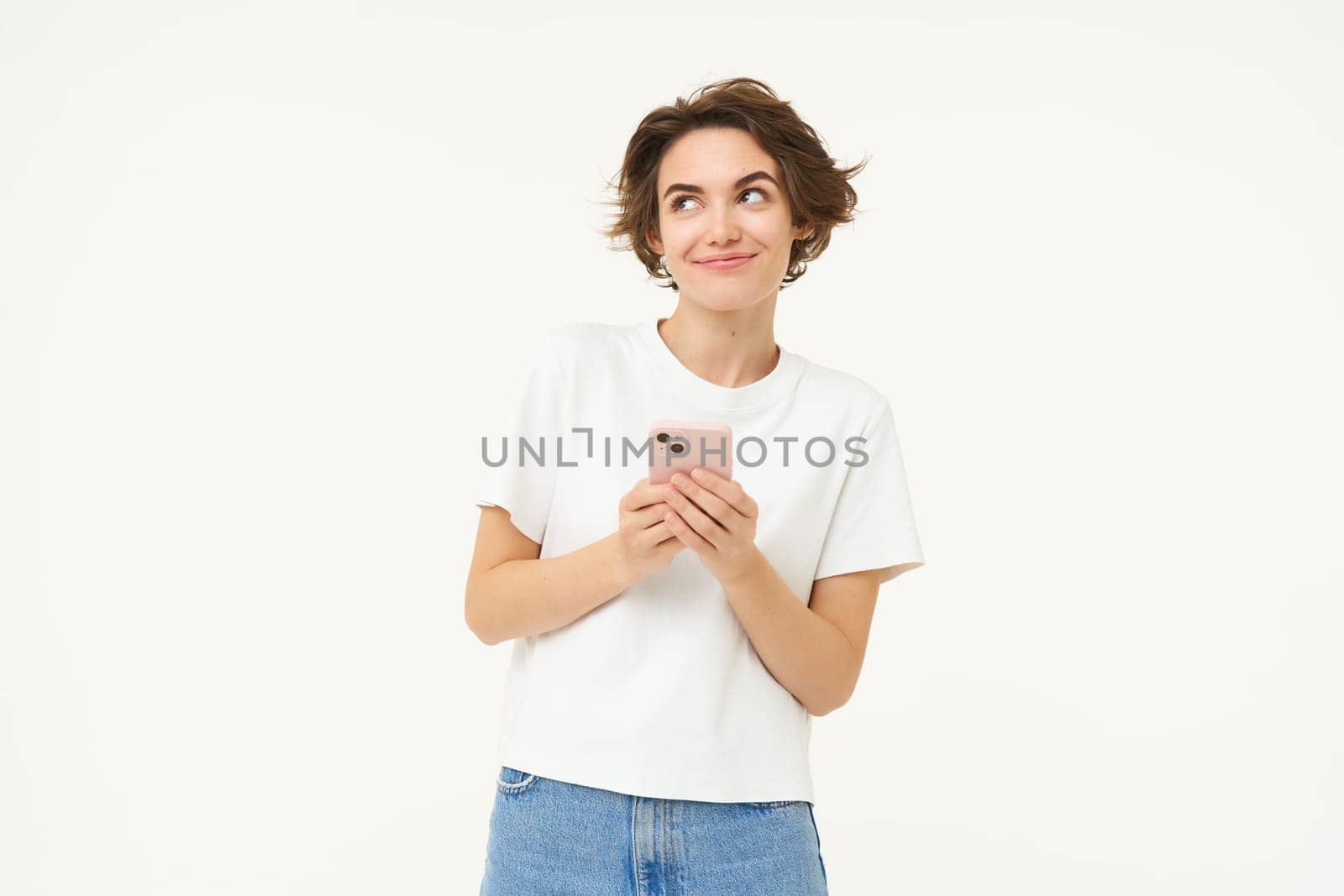 Portrait of cute modern woman with mobile phone, smiling, using smartphone app, doing online shopping on application, standing against white background by Benzoix