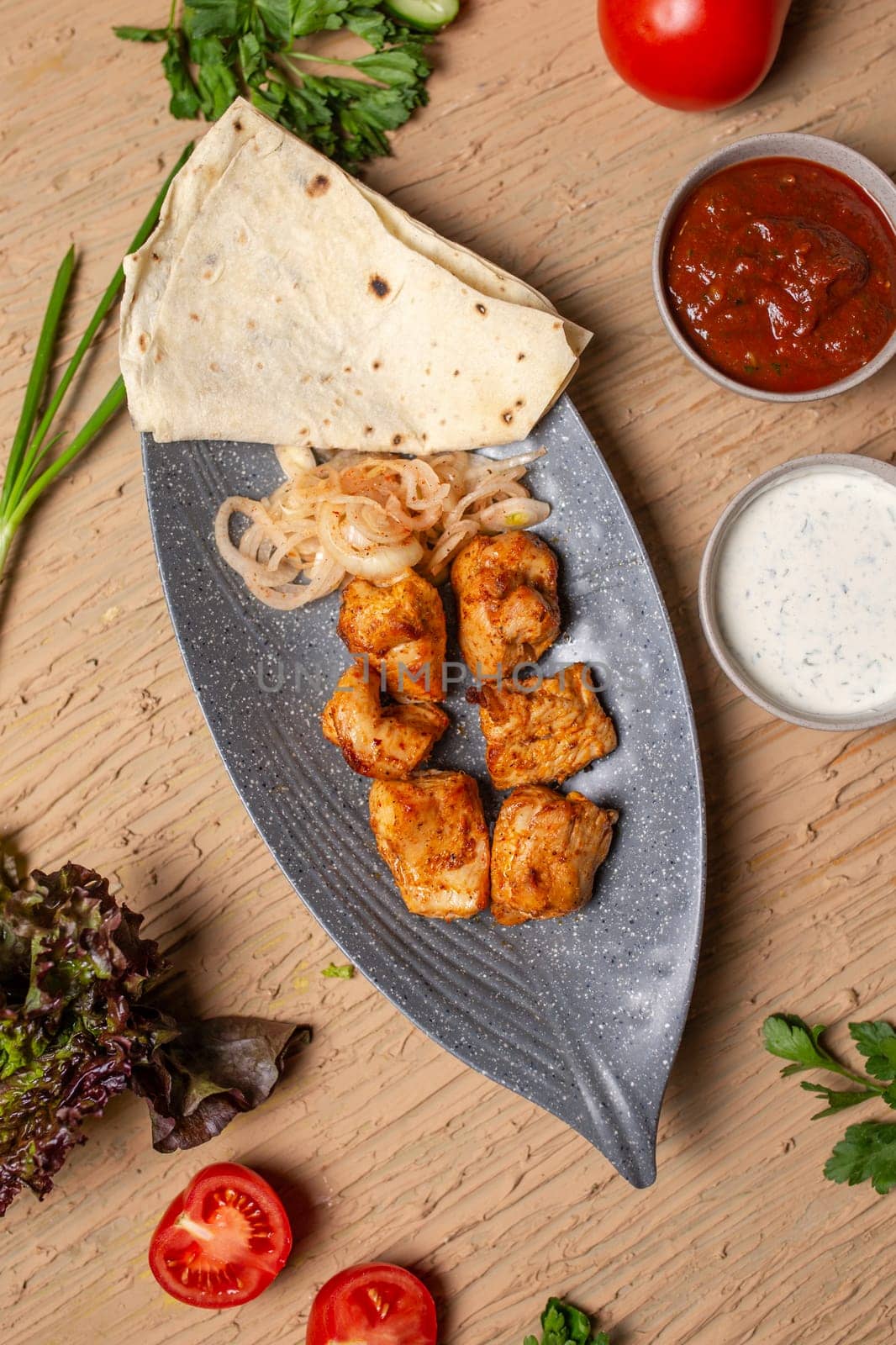 top view of a chicken kebab with sauce in a plate on a table in a restaurant by Pukhovskiy