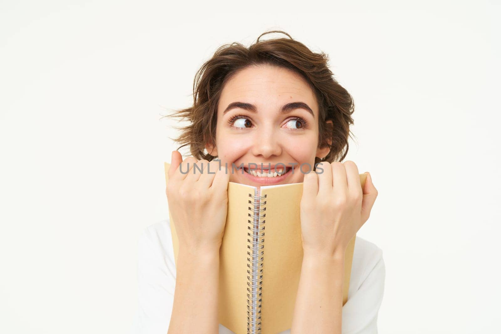 Portrait of happy woman with planner, holding notebook, reading notes and smiling, standing over white background by Benzoix