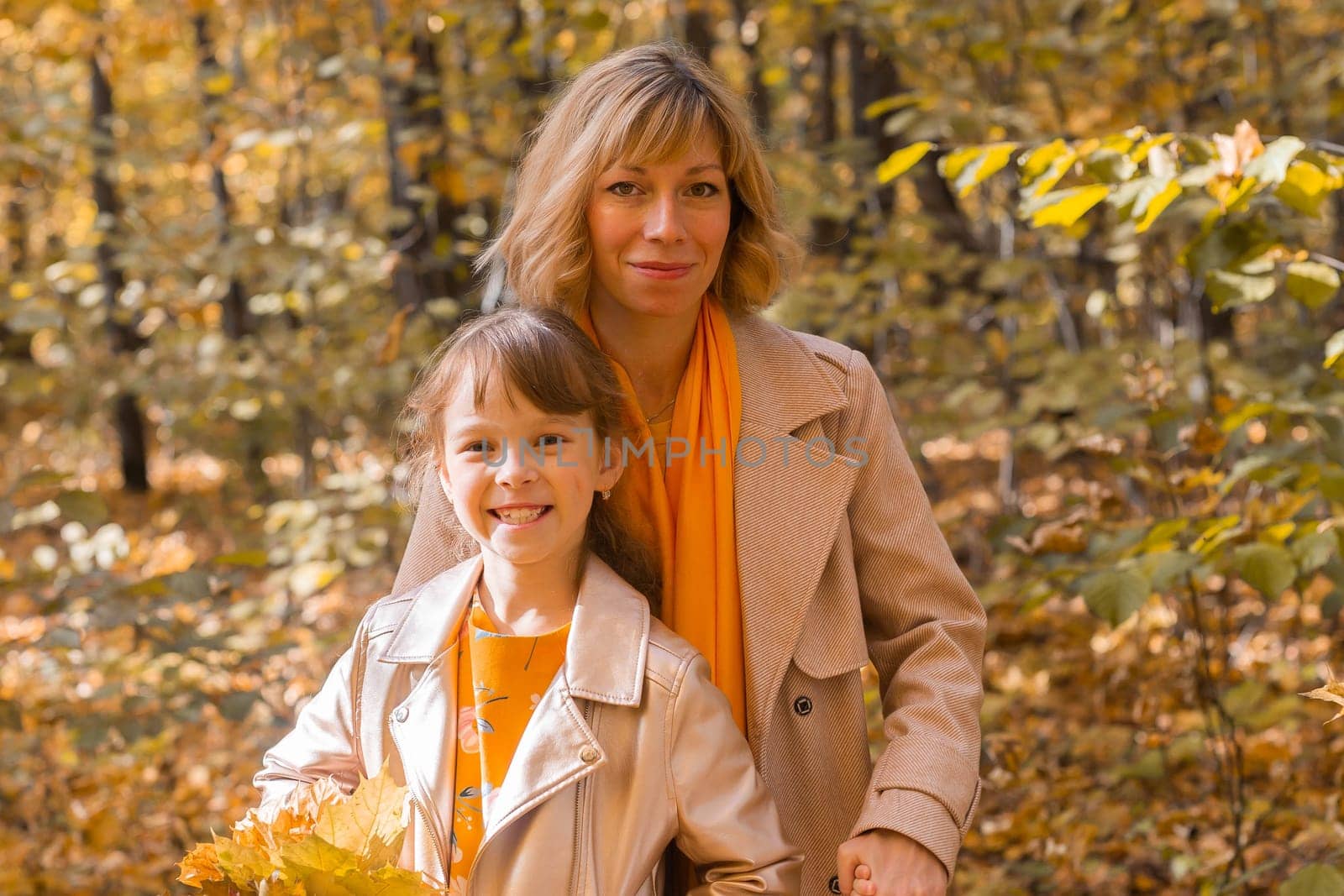 Beautiful lifestyle autumn photo mother and child walks evening in the park, warm sunlight