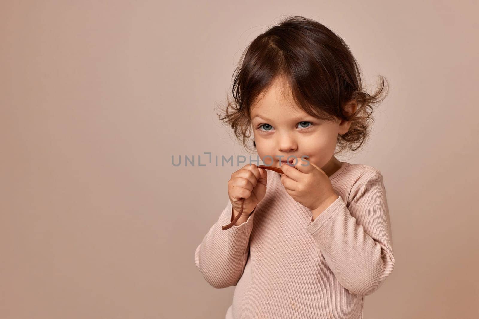 happy child girl holding fruit pastille on beige background. healthy baby food.