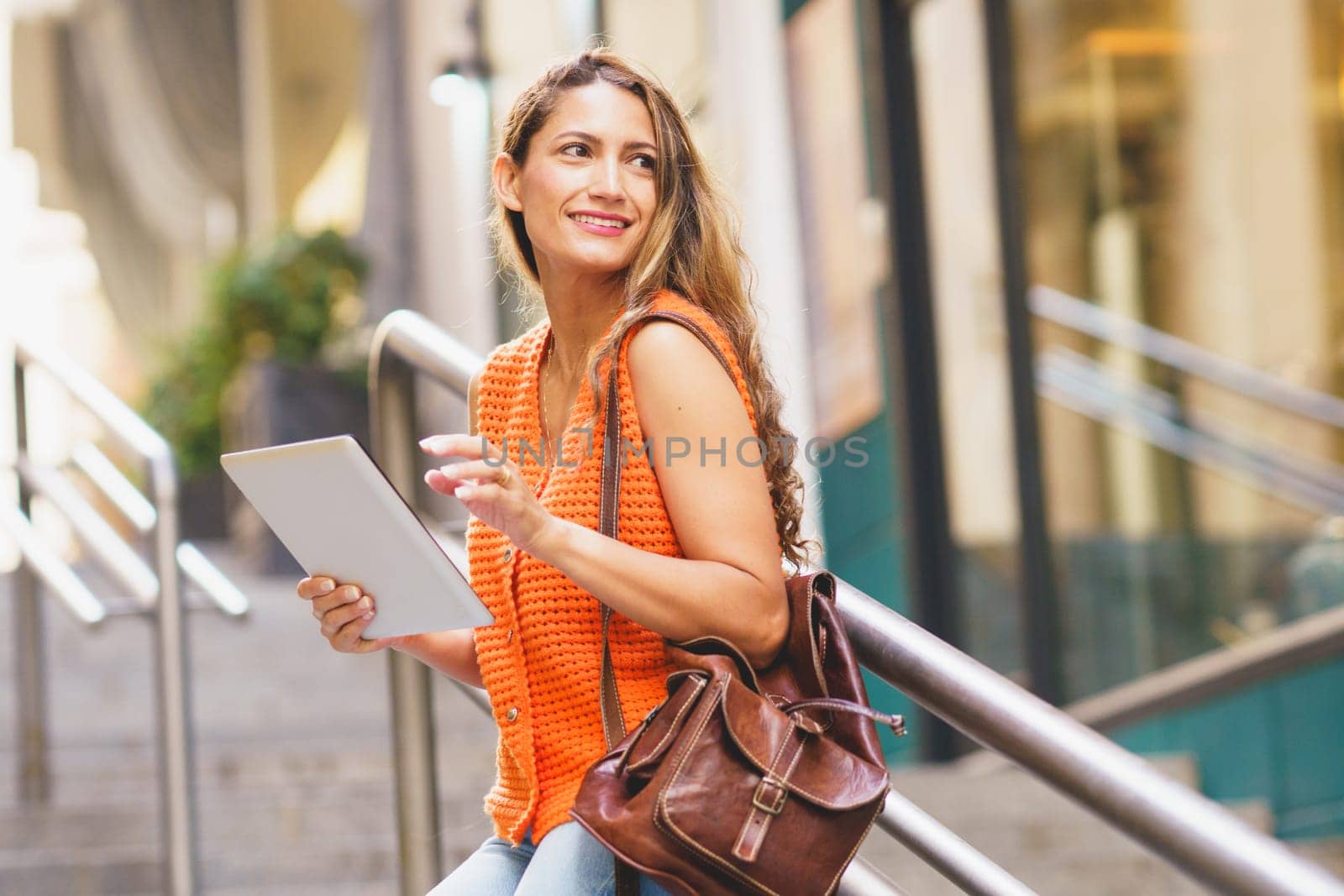 Side view low angle of a beauty latin woman using tablet standing in the city