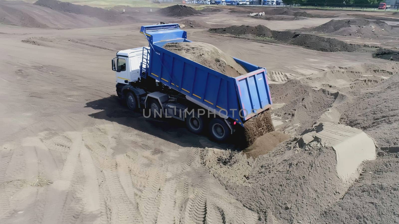 Top view of dump truck unloading sand. Scene. Dump truck dumps sand or earth on construction site. Land for construction site.