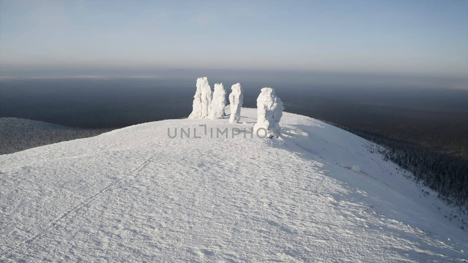 Stone pillars on hill in winter. Clip. Top view of stones standing on hill in winter. Snow-covered stone pillars on mountain on sunny winter day.