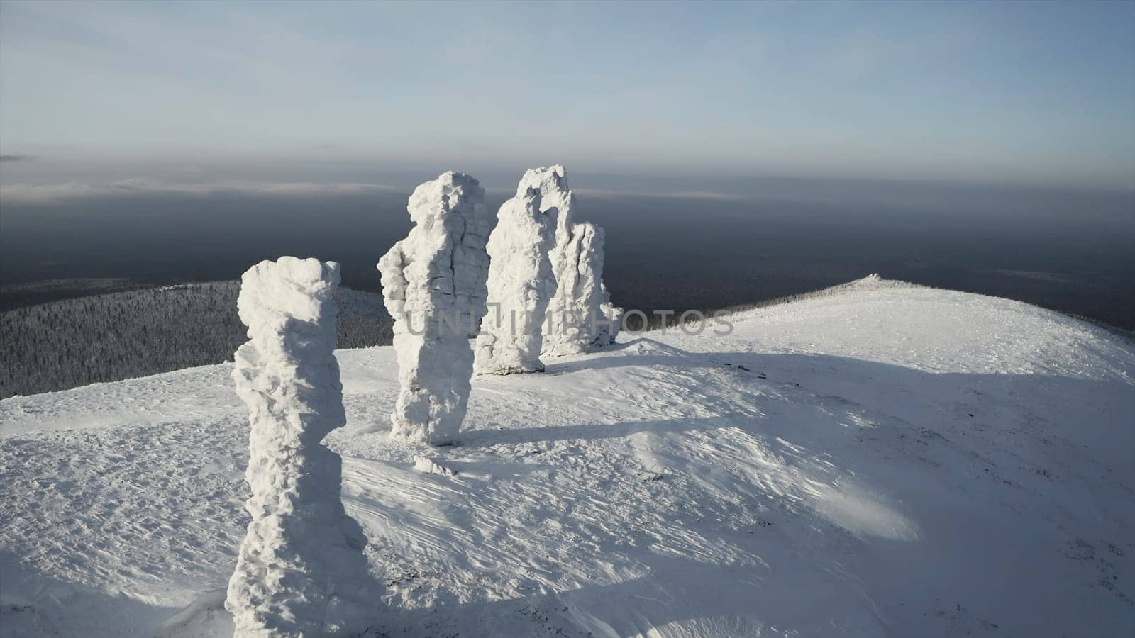 Stone pillars on hill in winter. Clip. Top view of stones standing on hill in winter. Snow-covered stone pillars on mountain on sunny winter day.