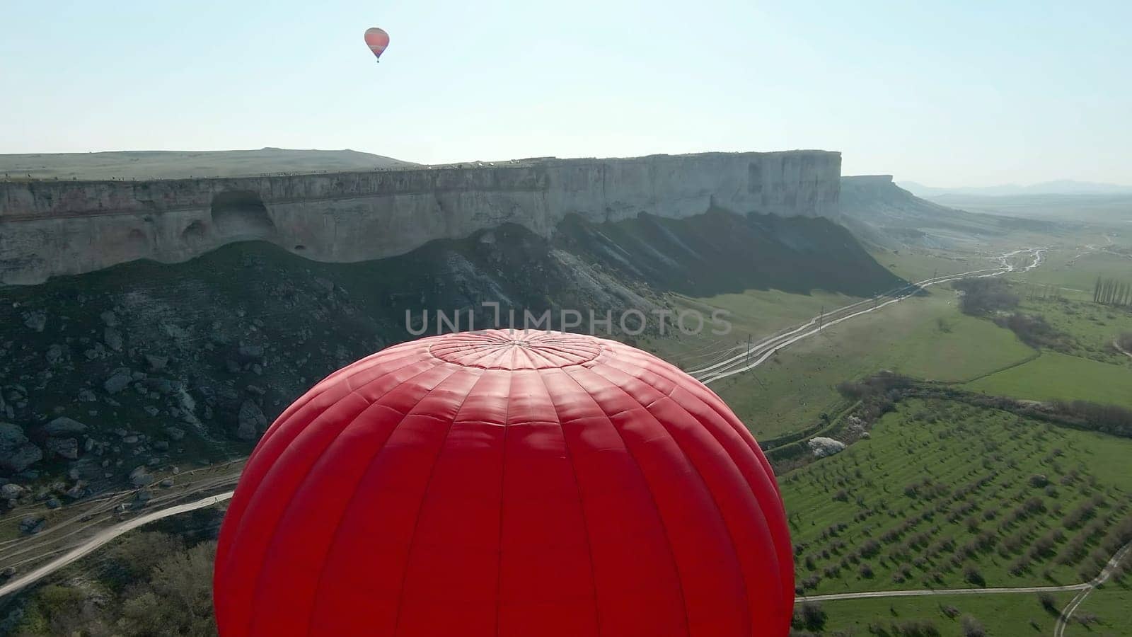 Top view of balloon at dawn with rock. Shot. Summer balloon festival at dawn. Balloons in green summer field with rock.