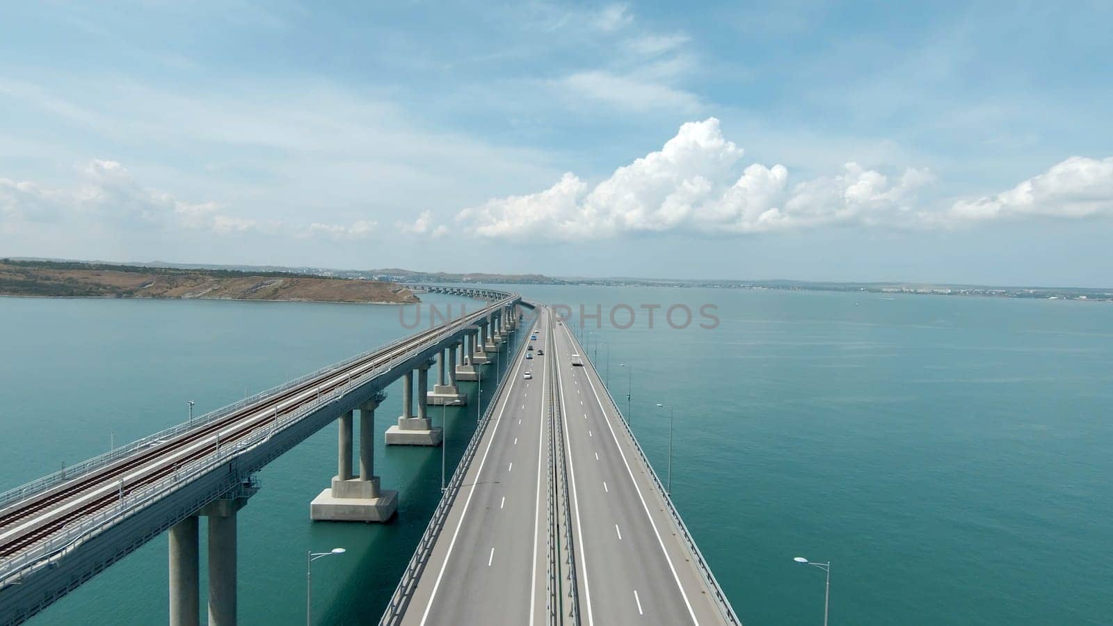 Top view of beautiful suspension bridge in sea. Shot. White bridge in turquoise sea on sunny day. Beautiful modern bridge with cars in sea strait.