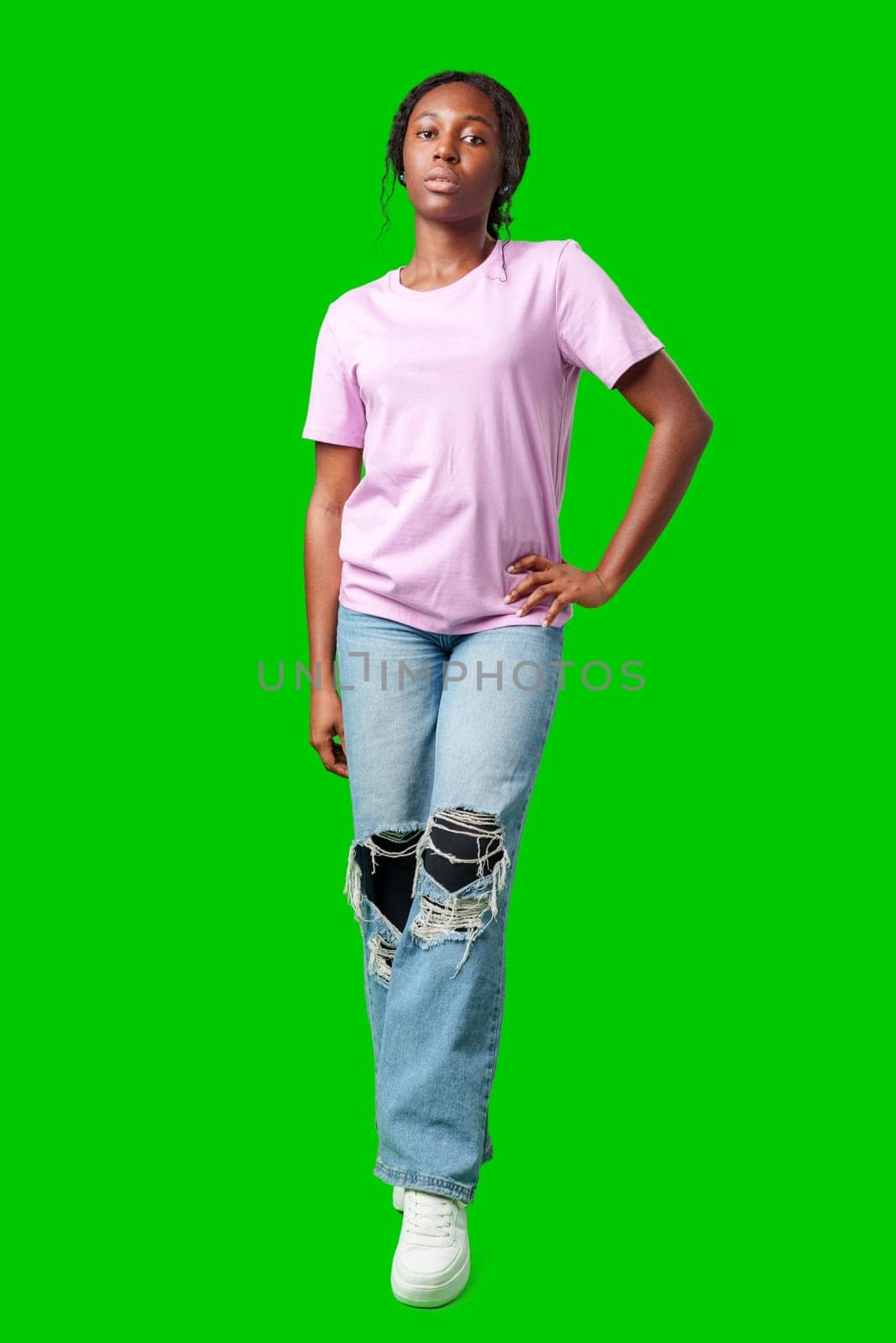 Young woman with curly hair shows a skeptical expression against a bright green background in studio