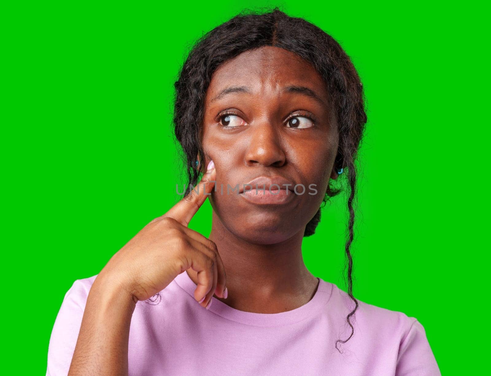 Thoughtful woman pondering in front of a bright green background during a casual moment close up