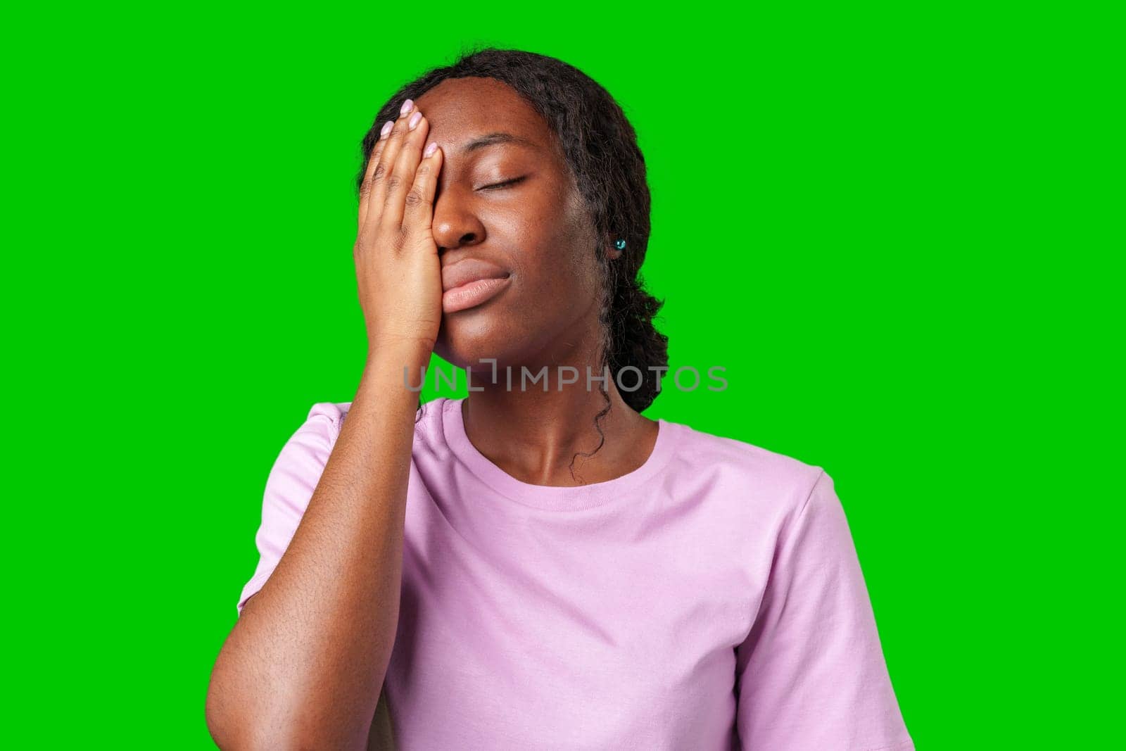 A woman expressing frustration while standing in front of a bright green background in studio