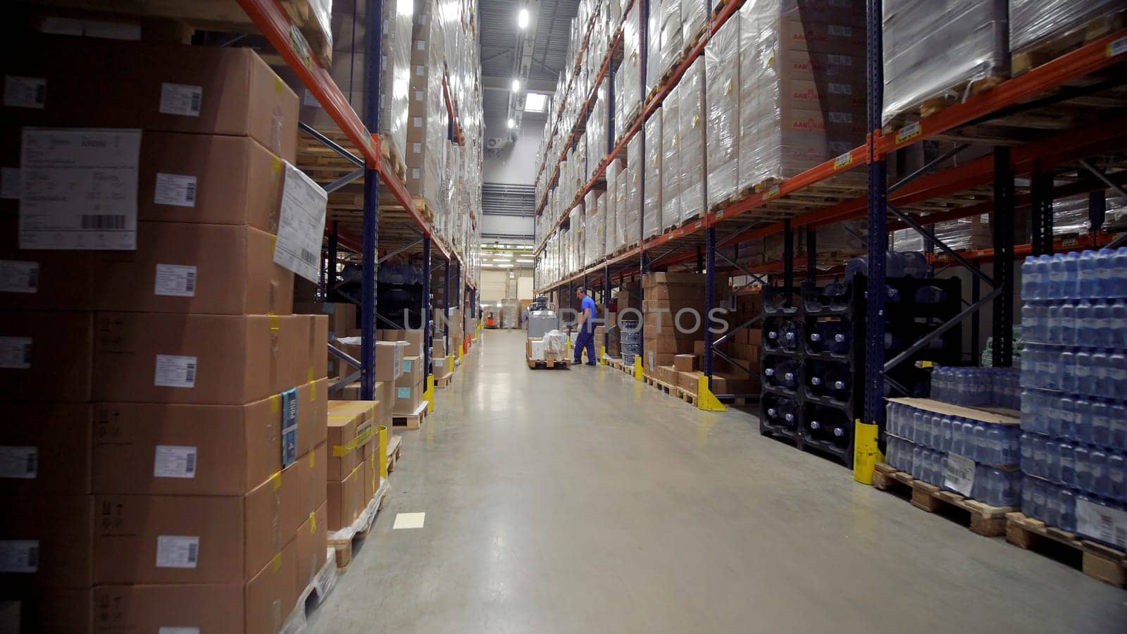 Moscow - Russia, 04.20.2022: Warehouse worker driver in uniform moving cardboard boxes by forklift stacker loader. Creative. Forklift pallet with boxes in large modern warehouse