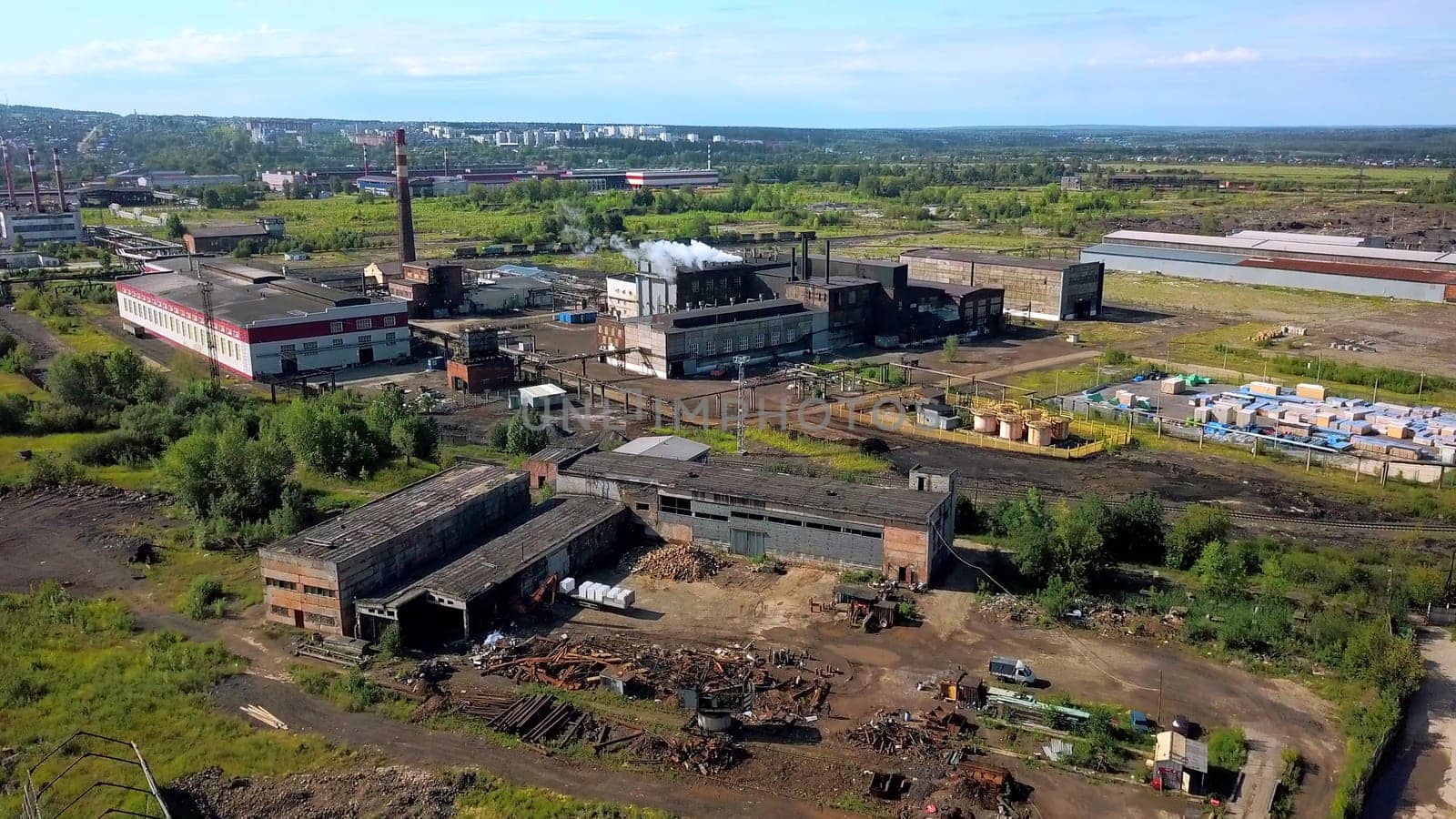 Urban industry from drone. Action. A view from a height to the outskirts with tall chimneys from where smoke comes out. High quality 4k footage