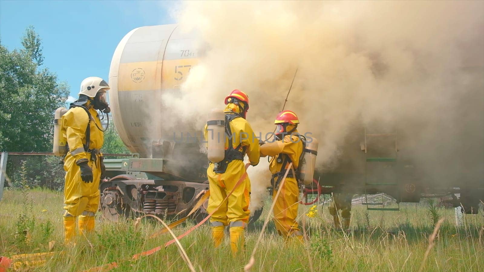 Firefighters and burning train. Clip. Firefighters are preparing with equipment to extinguish fire. Preparation for extinguishing industrial train car.