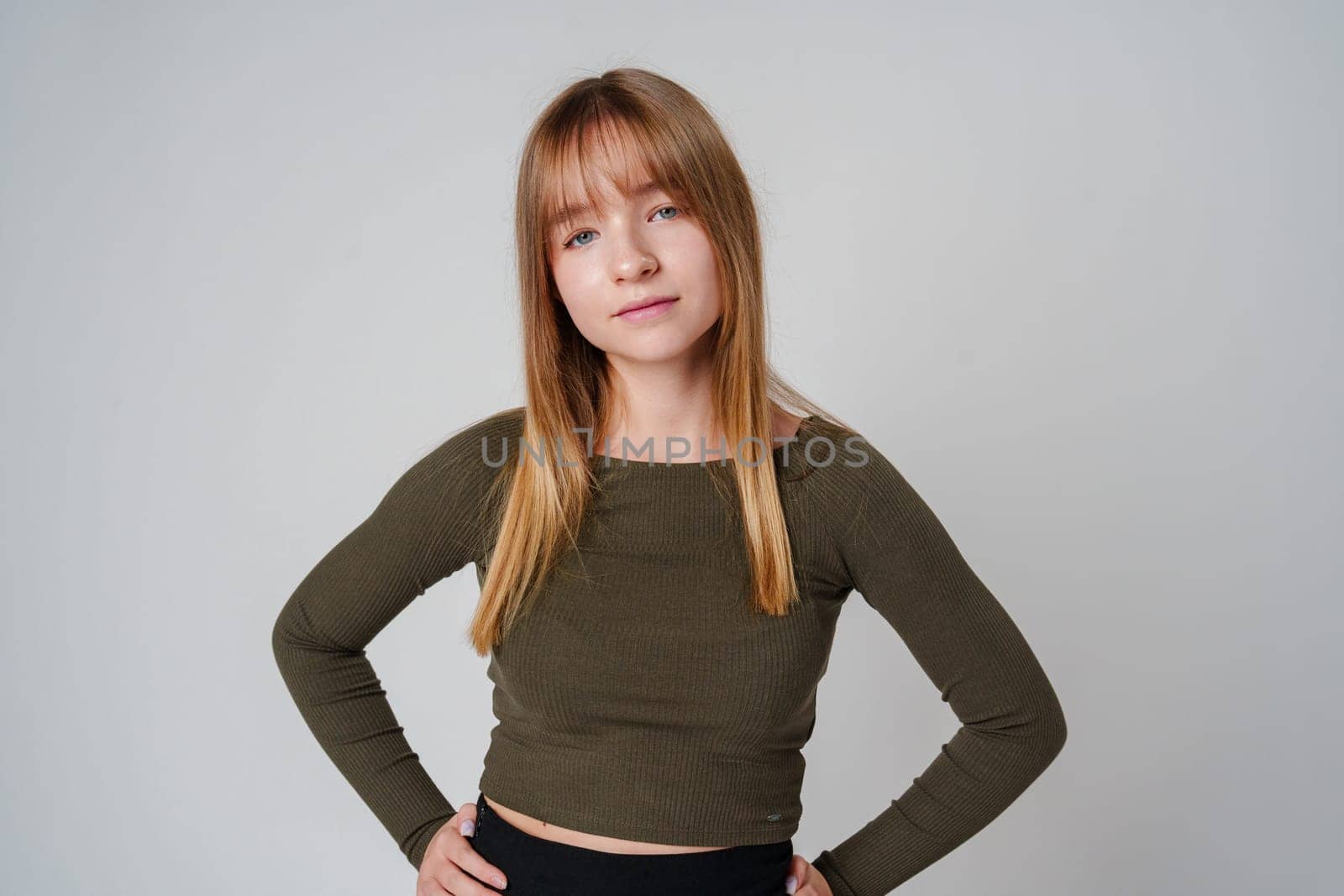 A young woman with straight hair wearing a green top poses against a neutral background in a calm setting