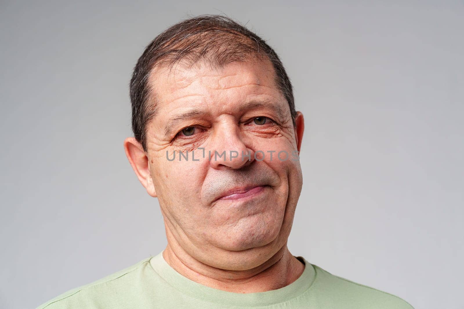 Middle-aged man with a thoughtful expression against a plain background close up