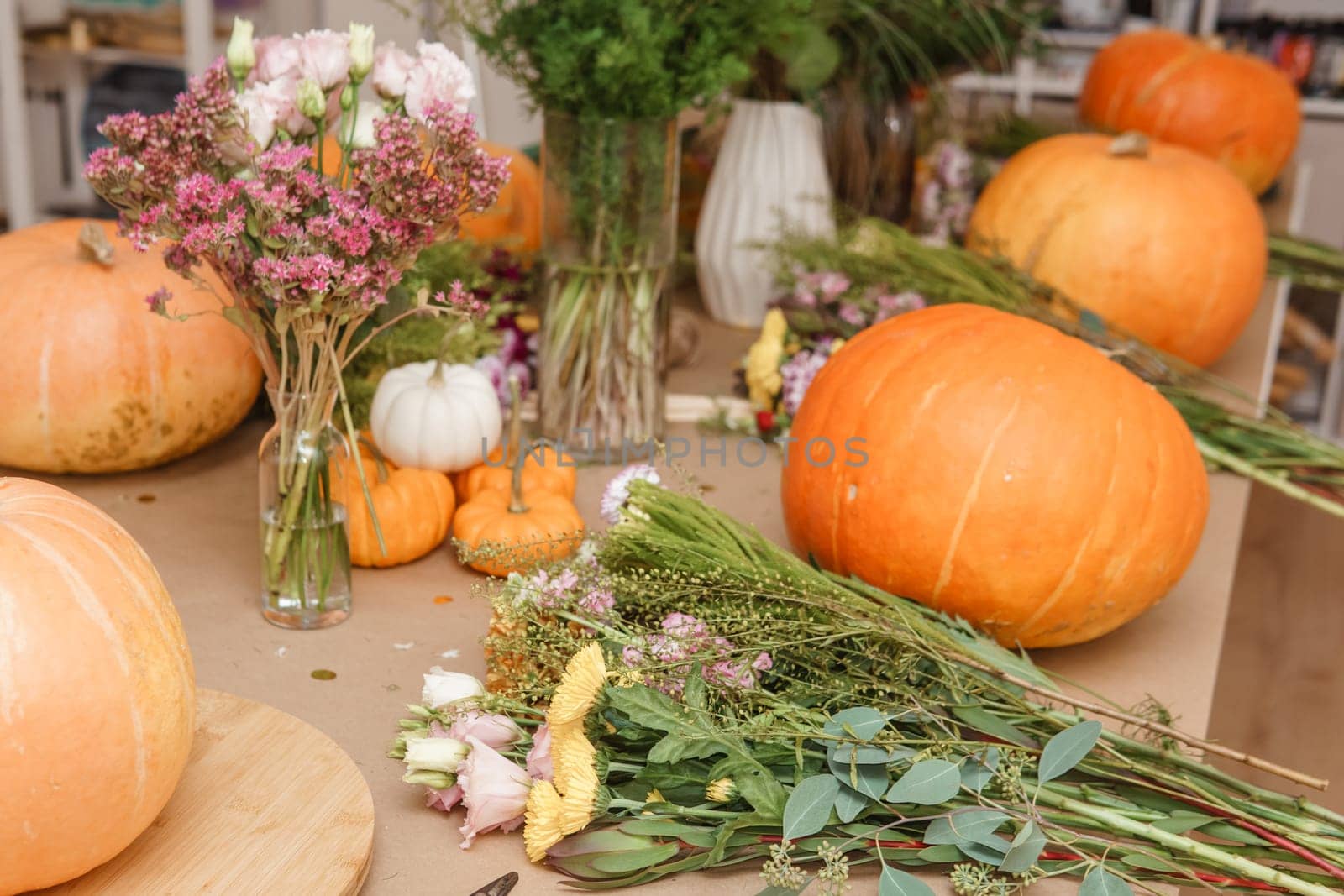 Flower arrangement in a pumpkin, autumn interior decor. Creating handmade autumn decor