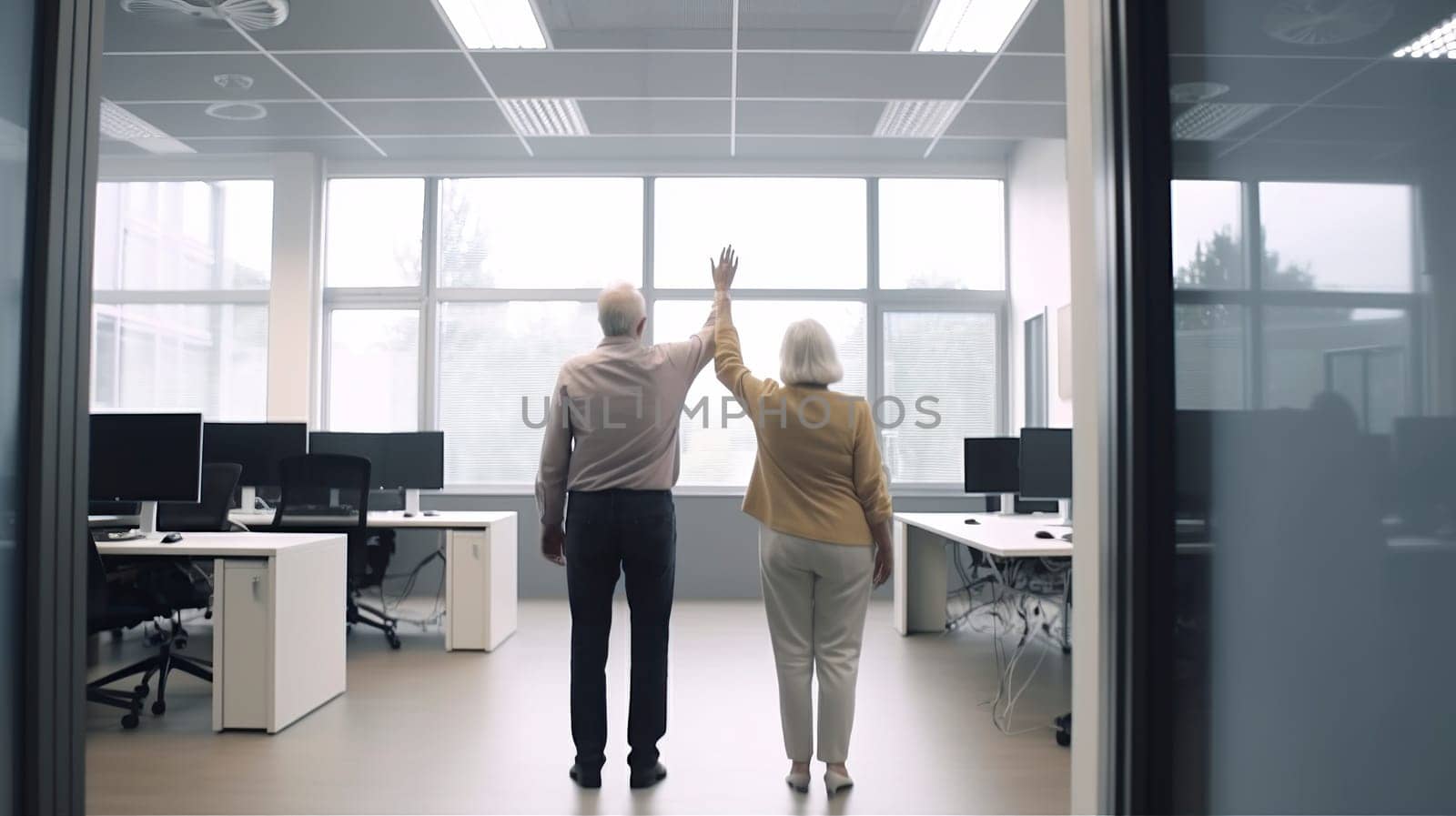 A man and a woman are both standing excitedly in an office, with their arms raised high in the air, celebrating a significant achievement or moment