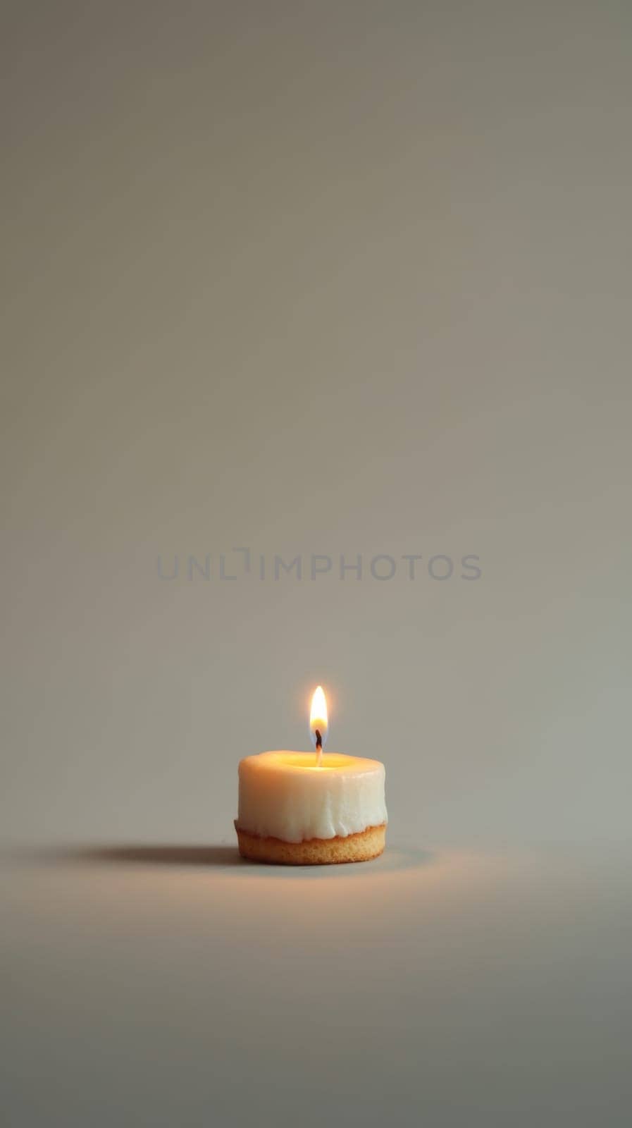 A small birthday cake with a single candle on minimalist background.