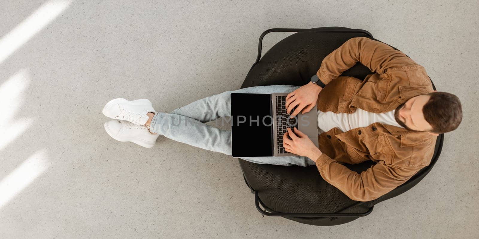 Male Freelancer Using Laptop Computer With Blank Screen Sitting In Chair At Home. Technology And Gadgets, Freelance Career And Lifestyle Concept. Top View Shot, Panorama, Mockup