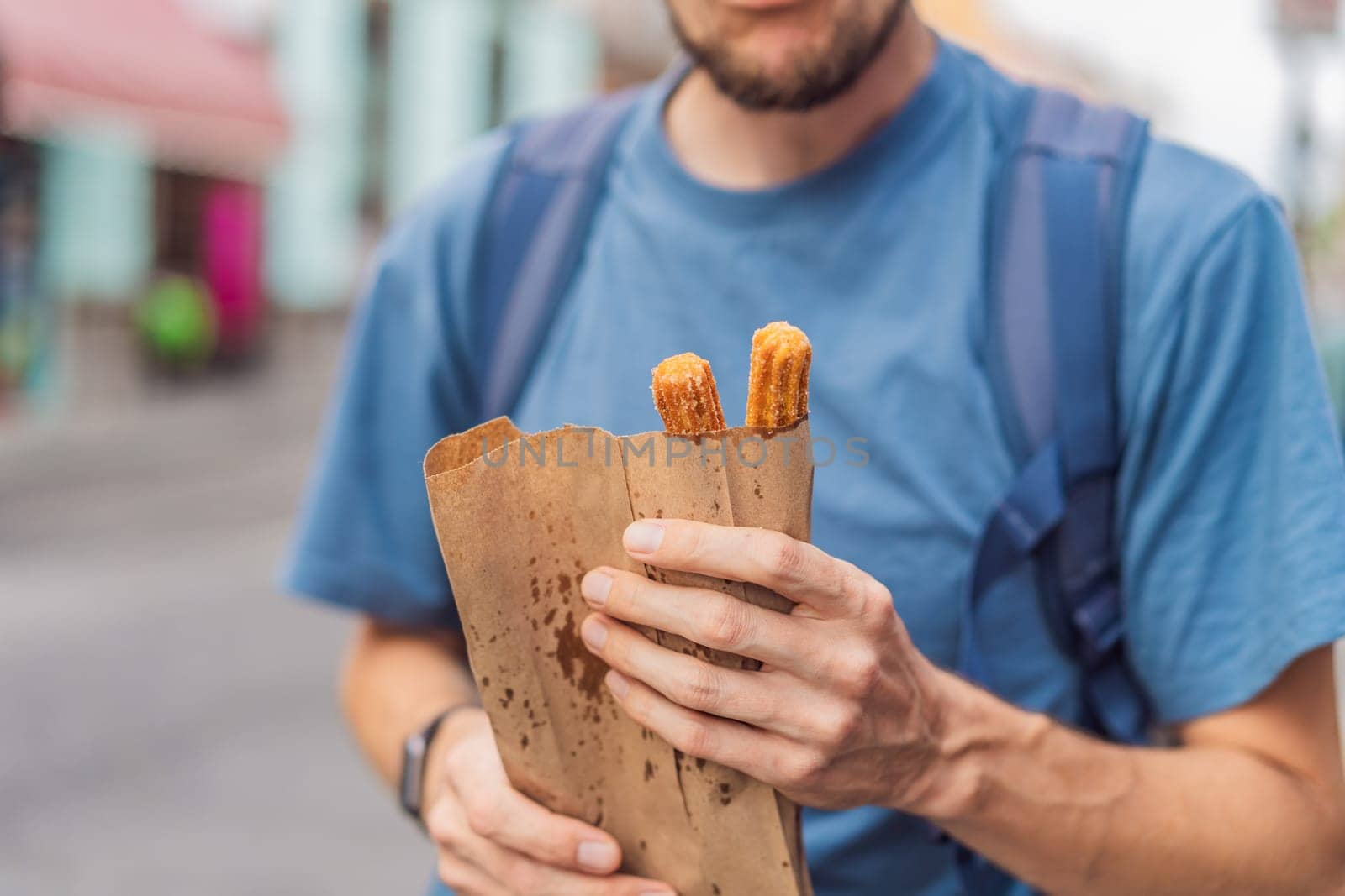Male tourist eating churros on a colonial street in Puebla, Mexico. Cultural experience, local cuisine, and street food exploration concept.