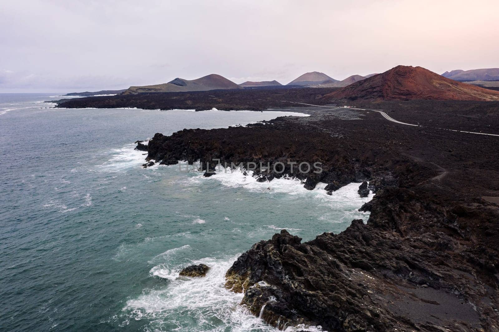 drone view of foamy sea breaking over the volcanic coast of Los Hervideros in Yaiza, Lanzarote at Canary Islands, Spain, concept of wild nature