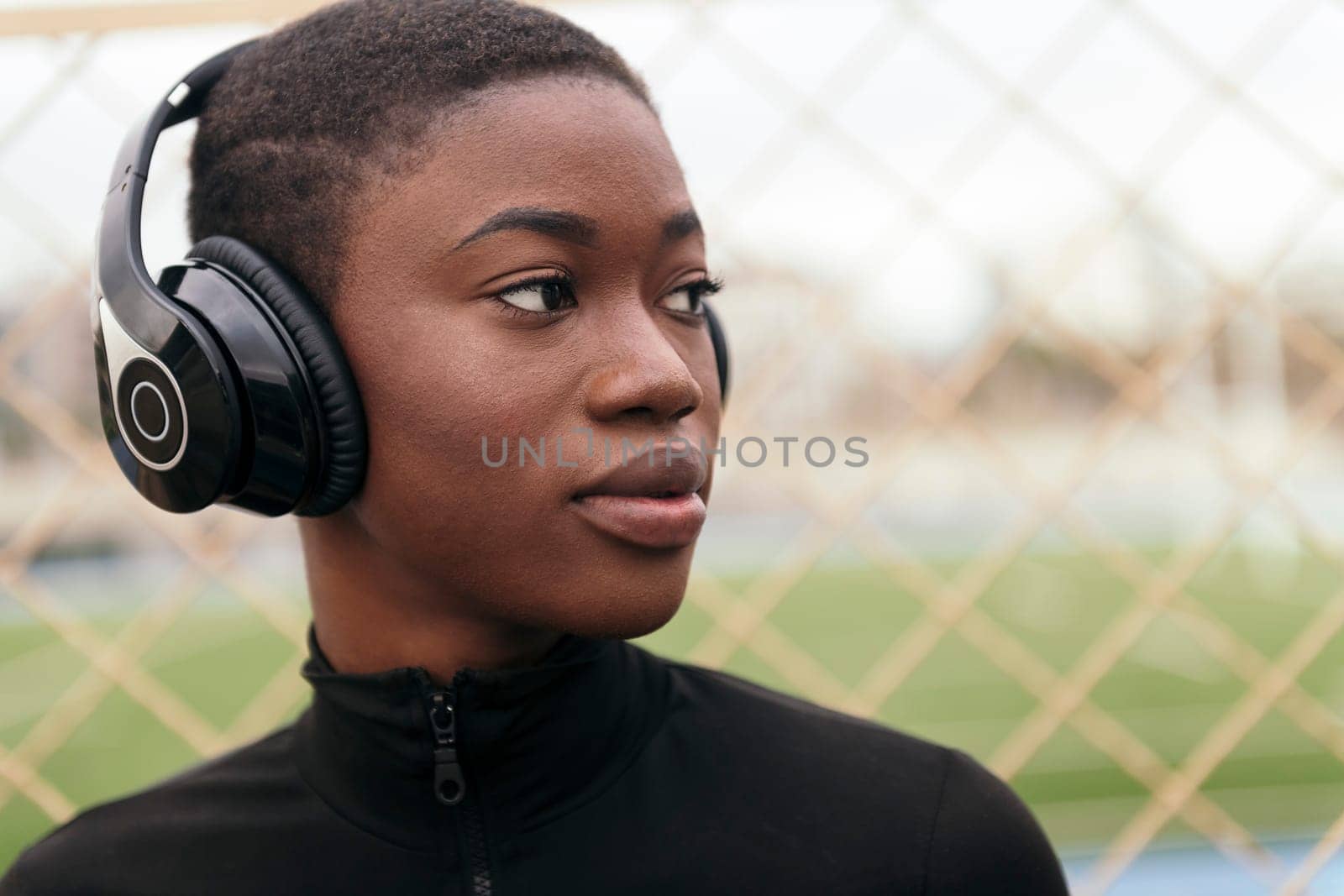 young glad african american woman enjoying music in wireless headphones while listening to song in city, copy space for text