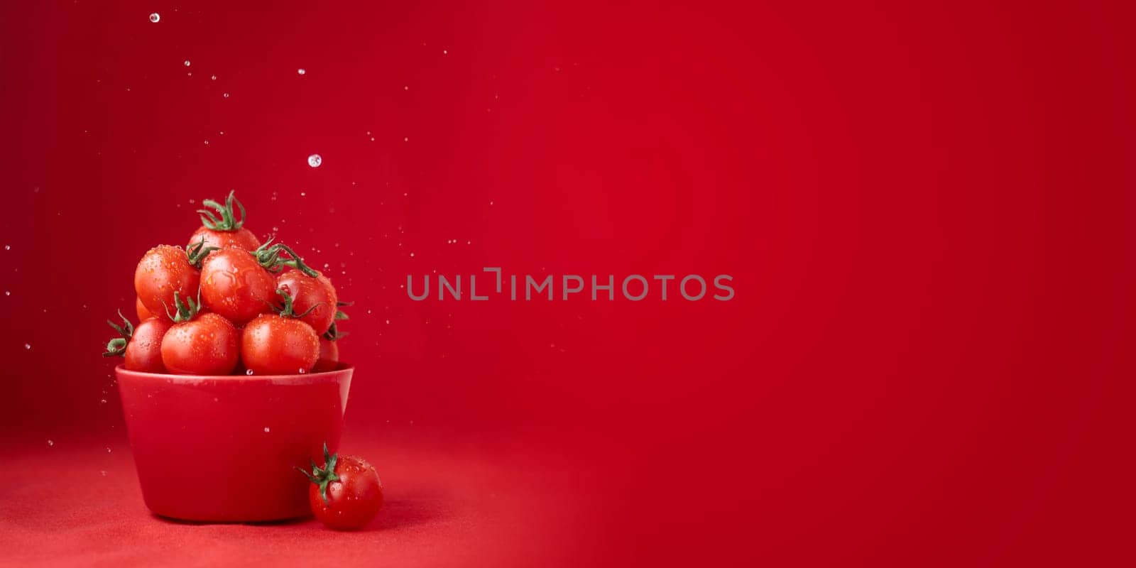 Creative food concept. Tomatoes pattern. Red ripe juicy cherry tomatoes in red bowl with water drops on red background. Healthy fresh vegan organic food, vegetable, summer, harvesting with copy space