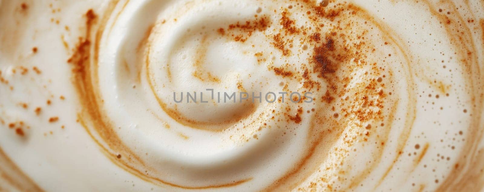 Close-up of frothy coffee with cinnamon swirl, textured surface. Warm beverage and autumn concept.