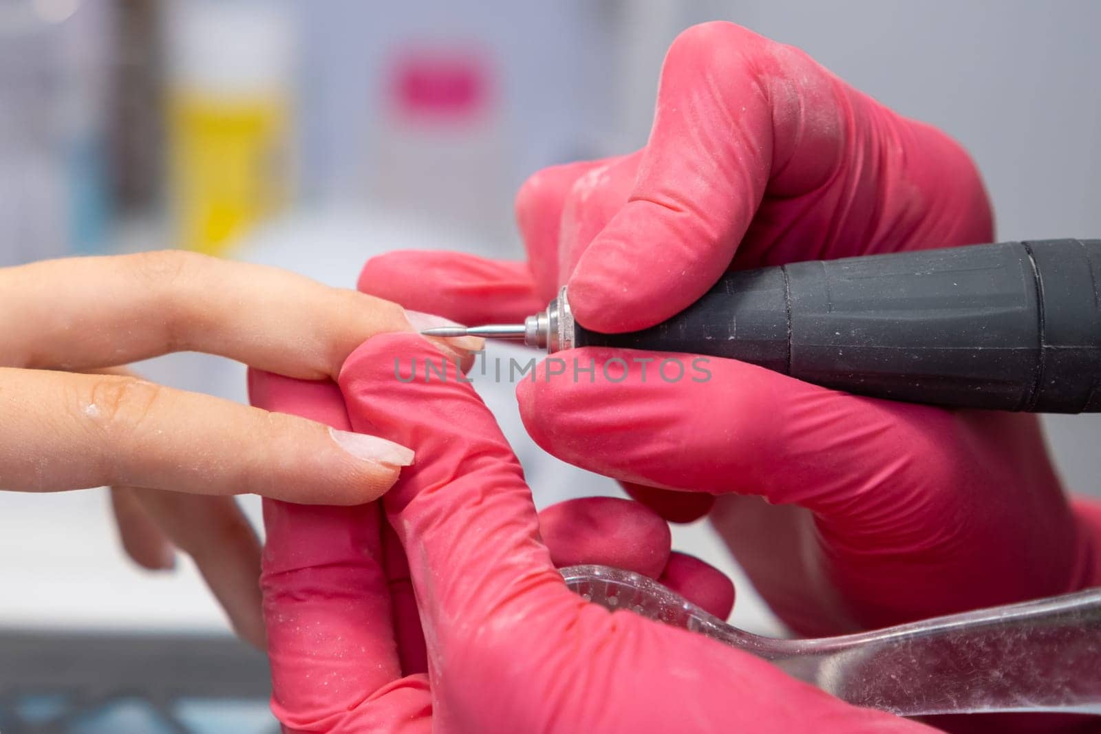 Manicurist uses a nail drill to perfect a woman hardware manicure in a beauty salon