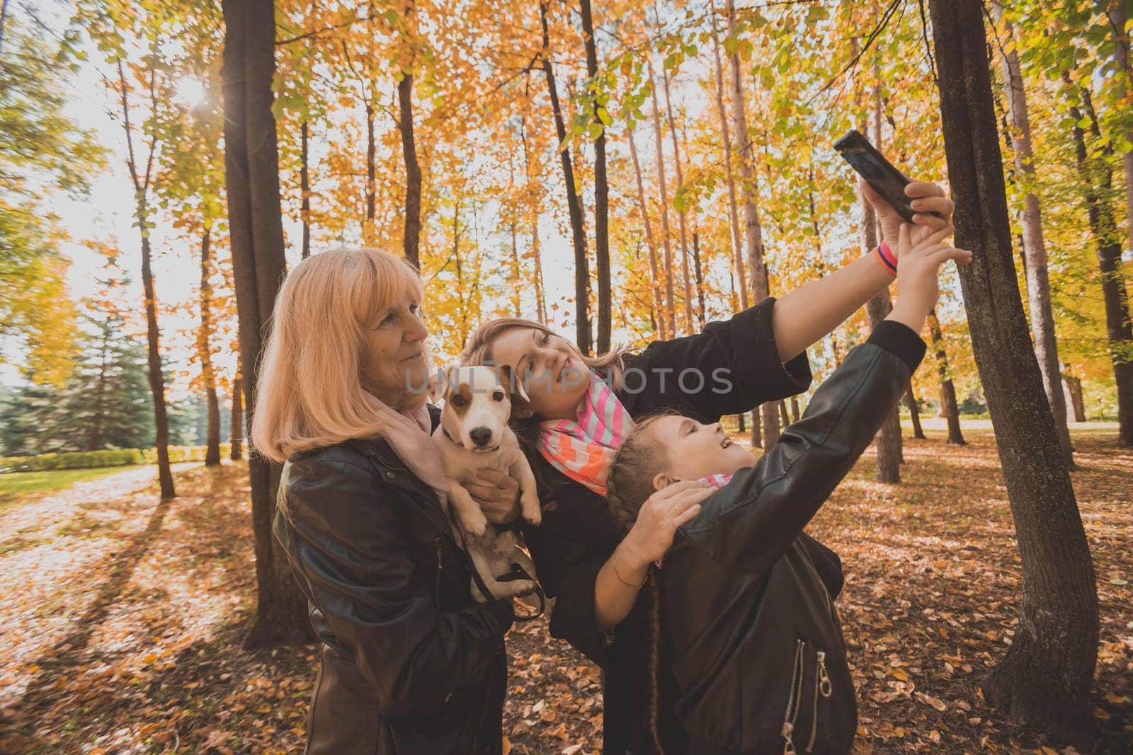 Three generations of women and dog feel fun look at camera posing for self-portrait picture together, funny excited child, mom and grandmother have fun enjoy weekend take selfie on gadget in autumn by Satura86