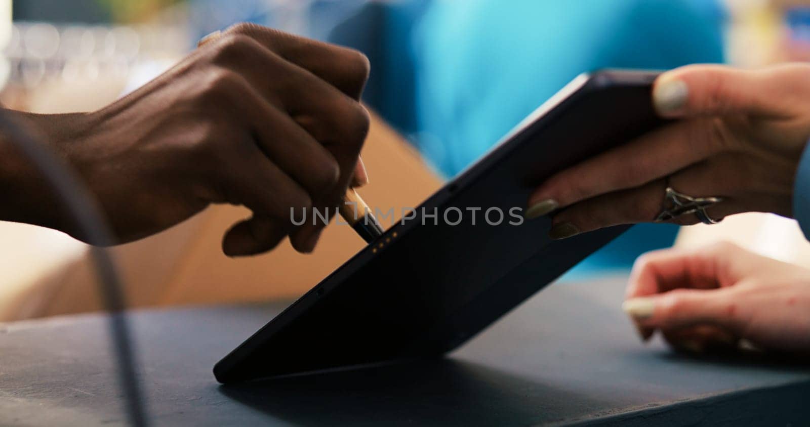 African american courier signing shipment document on tablet computer in modern boutique, discussing distribution details with worker. Manager working at online orders, preparing packages for delivery