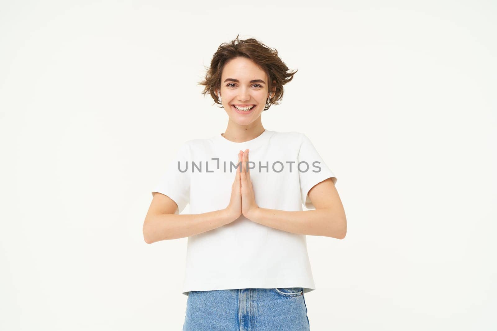 Portrait of brunette young woman holds hands together, namaste gesture, say thank you, grateful, express gratitude and joy, stands over white background. copy space