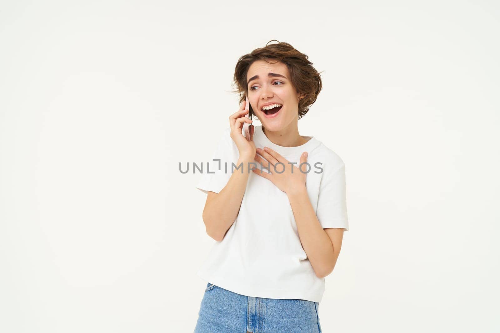 Happy woman casually talking on mobile phone and smiling, discussing something with friend over the telephone, white background.