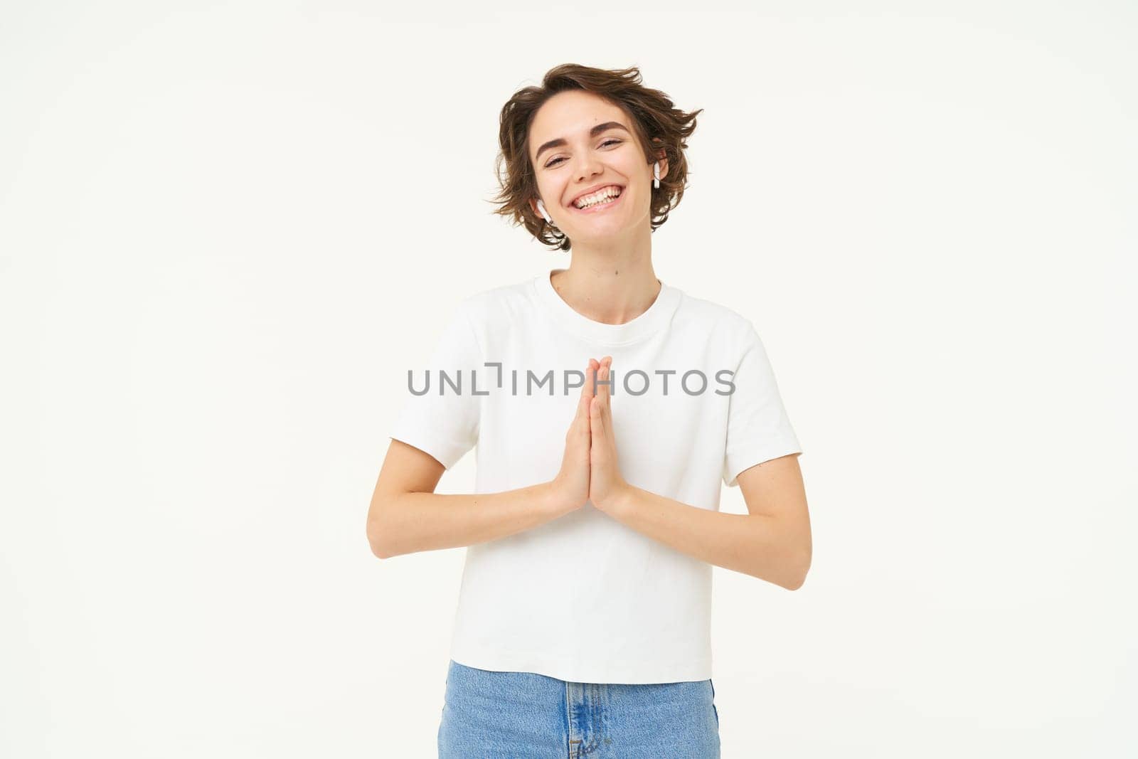 Portrait of brunette young woman holds hands together, namaste gesture, say thank you, grateful, express gratitude and joy, stands over white background. copy space