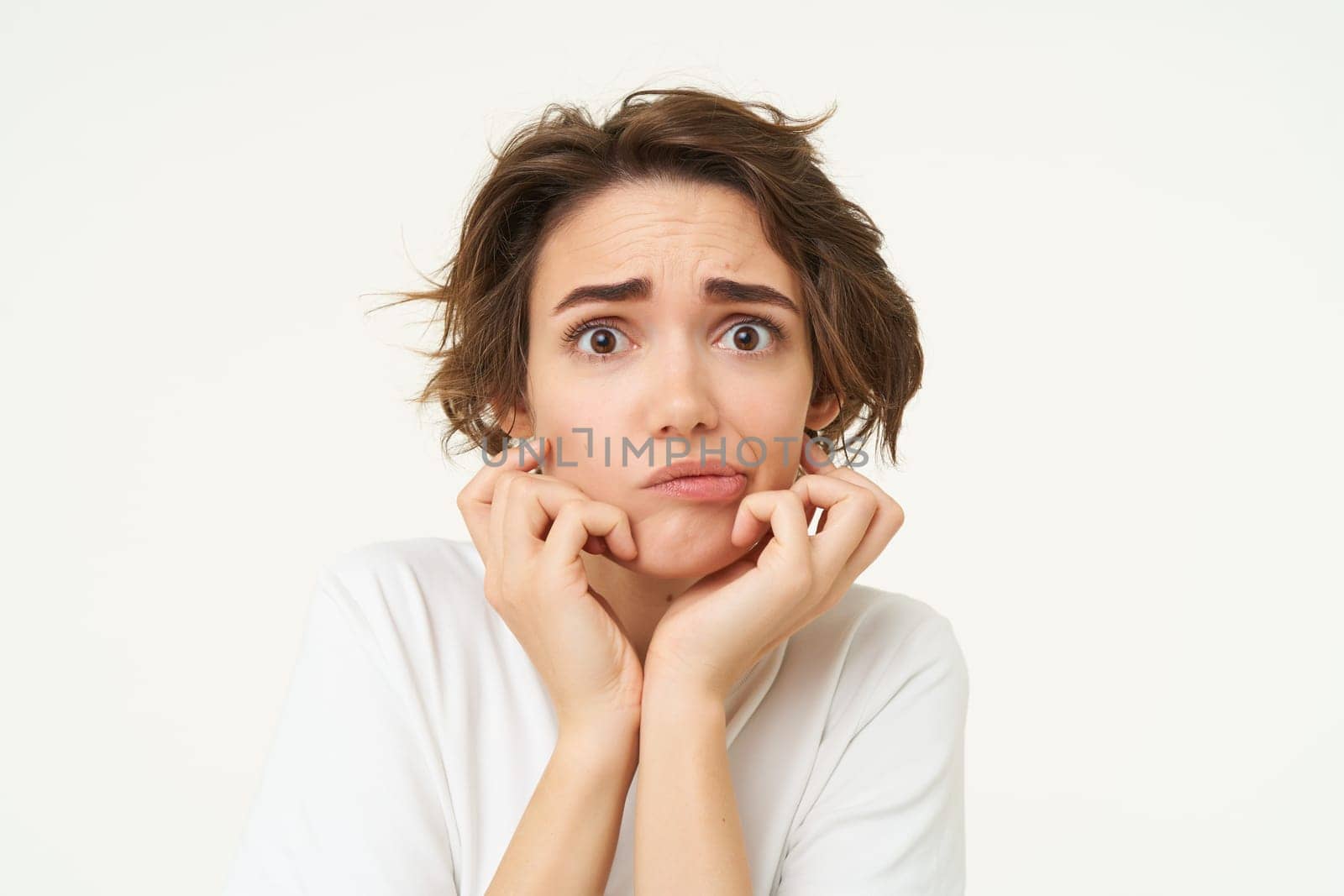 Close up of shocked, scared and worried young woman, trembling from fear, posing over white background.