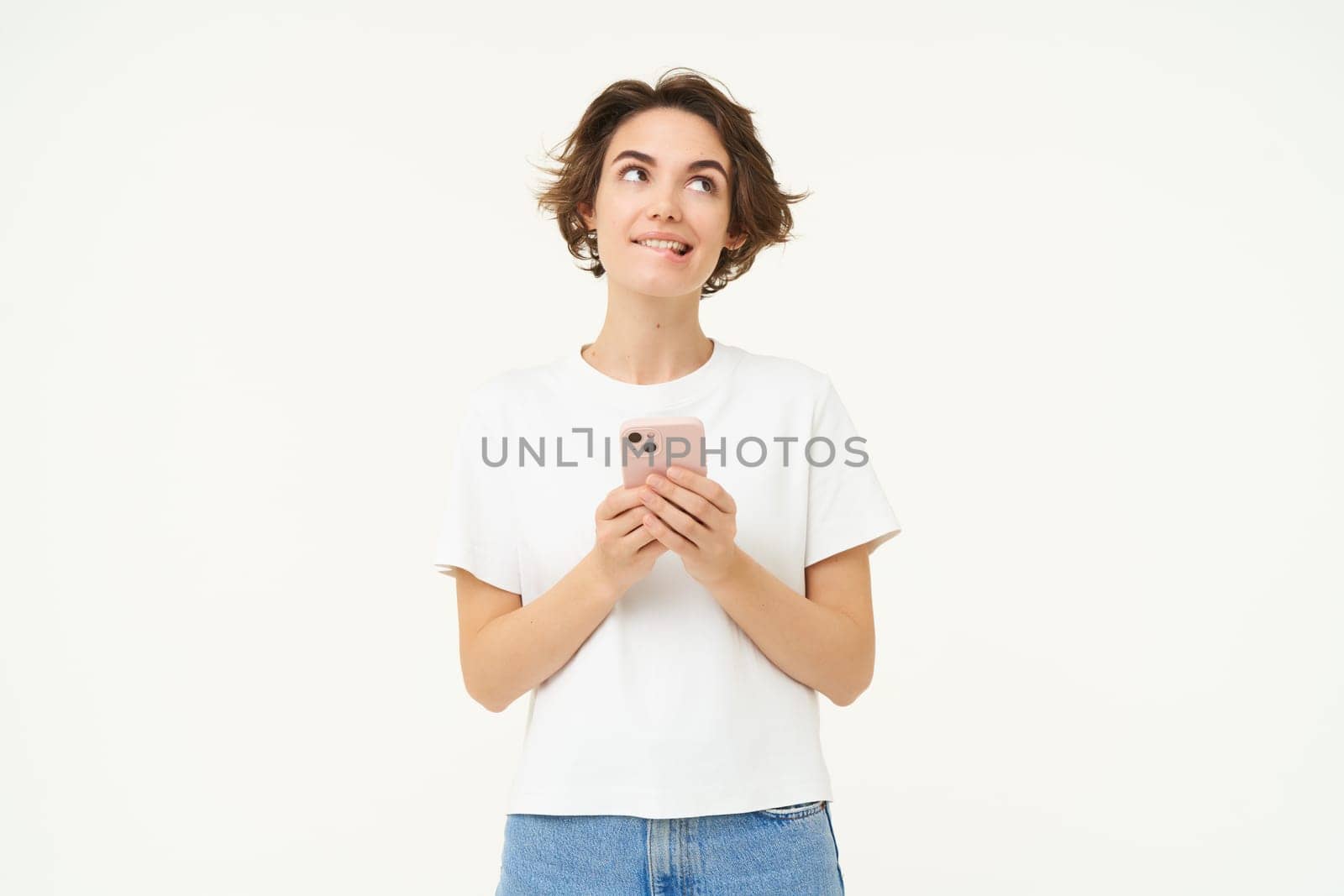 Portrait of brunette girl with smartphone, sending a message, using mobile phone application, smiling and looking happy, white studio background by Benzoix